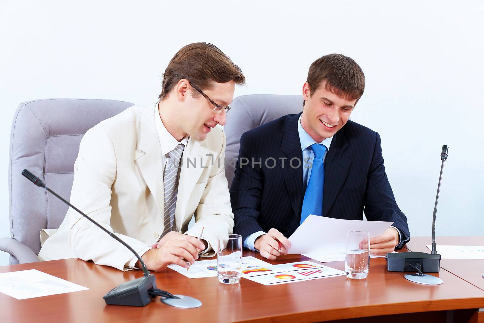 Image of two businessmen sitting at table at conference