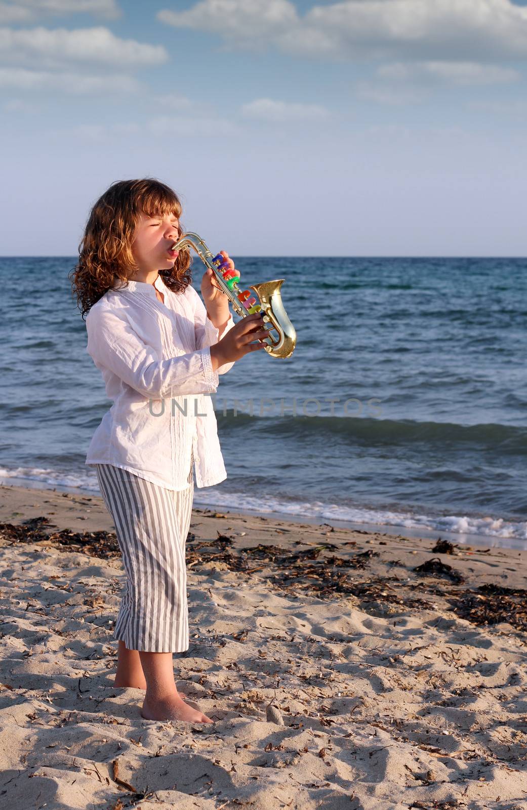beautiful little girl play saxophone on beach by goce