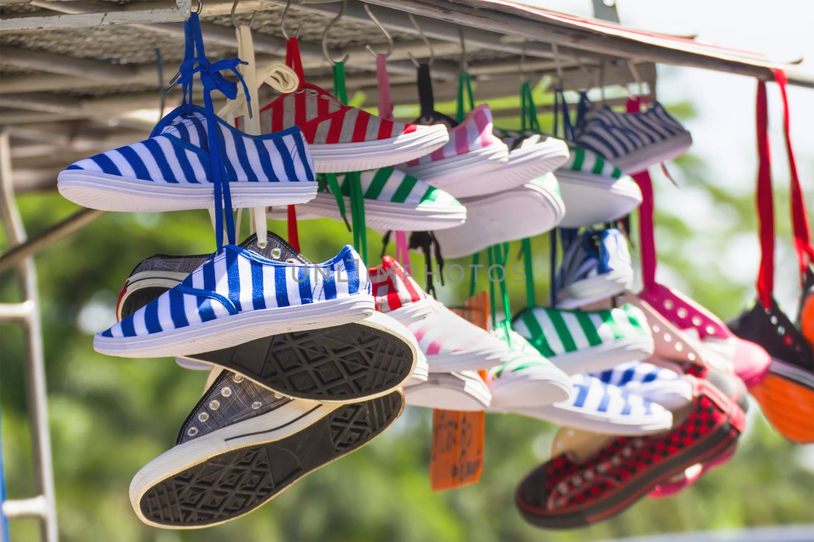 Lot of sneakers   shoes multicolored hanging on roof