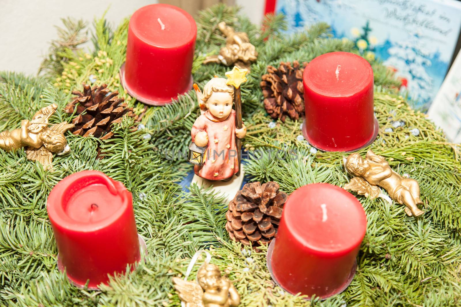 Christmas decorations with angel and red candles on tree branch.