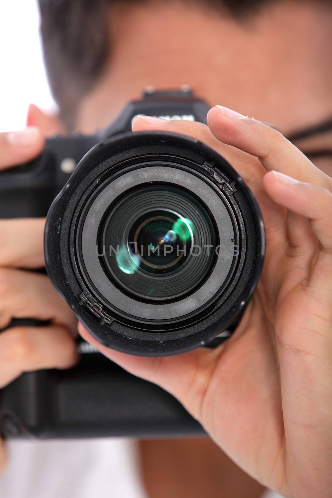 Man focusing his camera with the lens pointed directly at the viewer, close up view