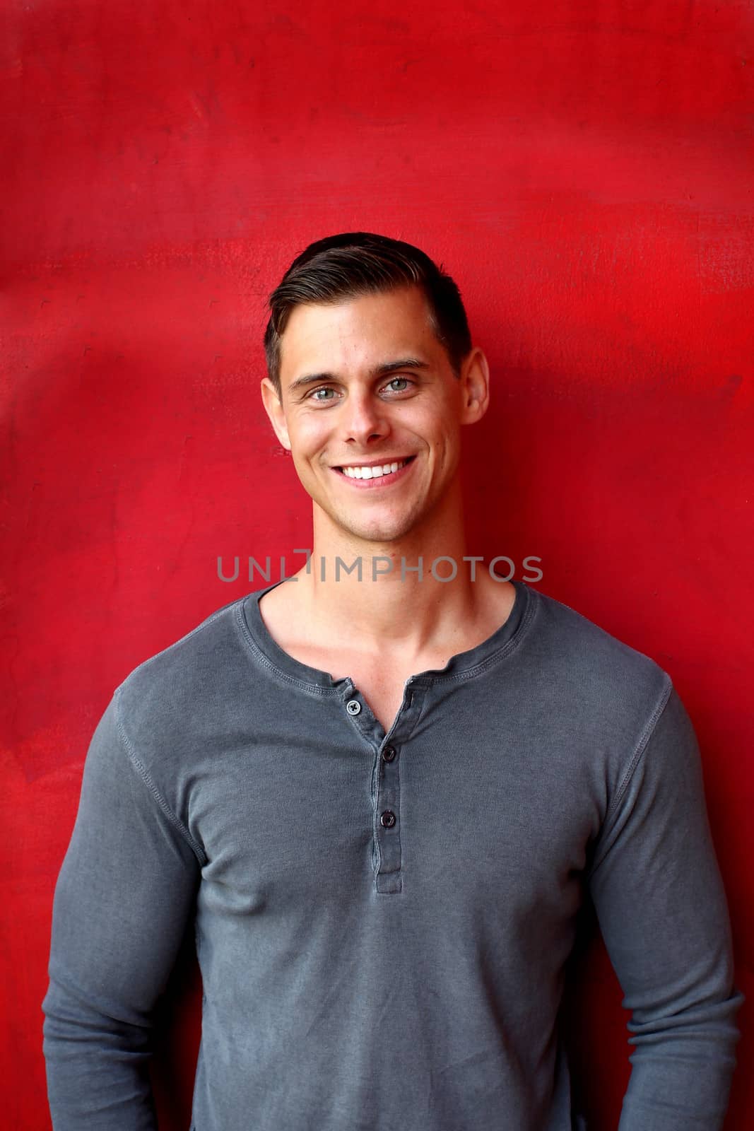 Portrait of a man with gray shirt in front red wall.