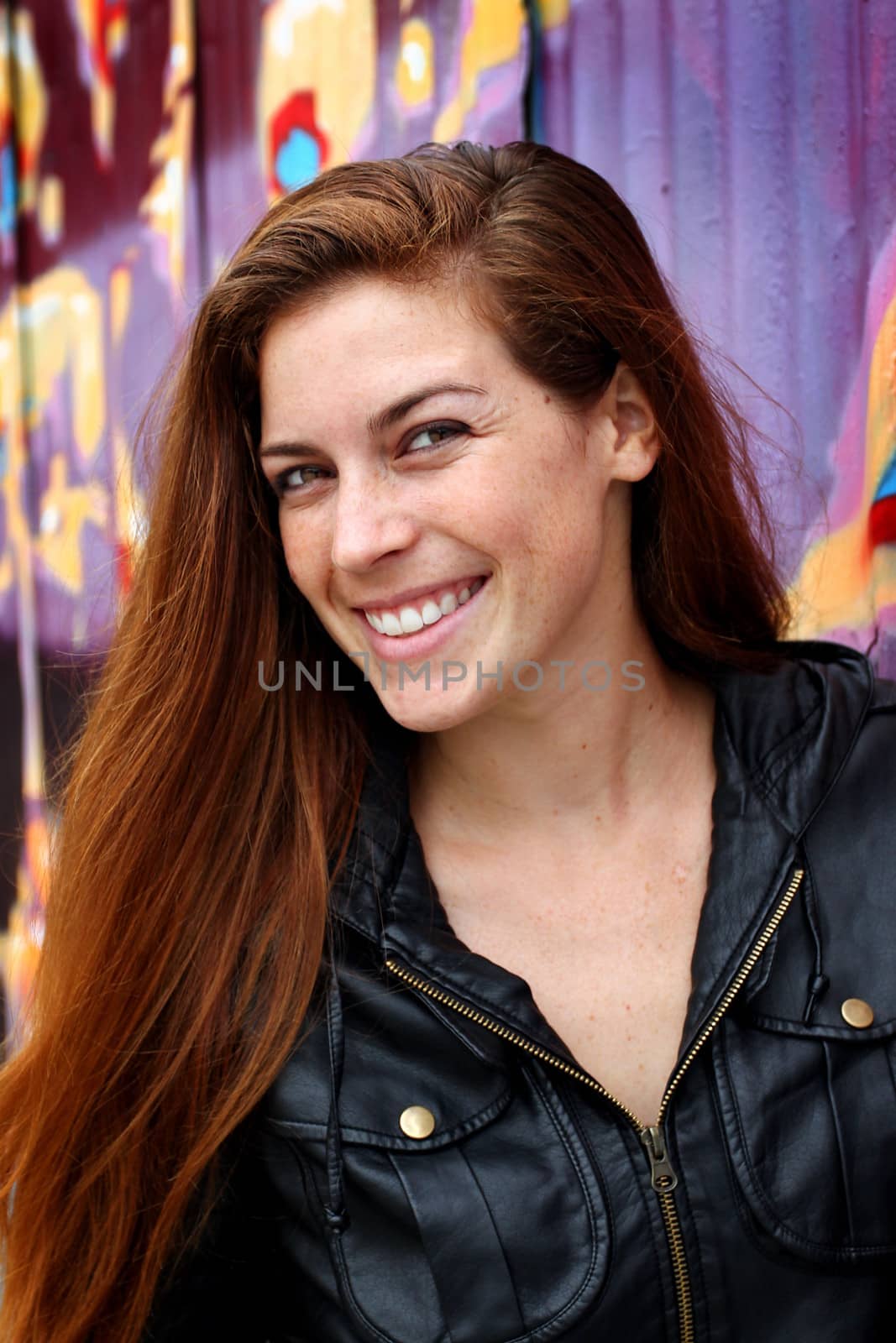 Portrait of a young woman infront of a colorful wall.