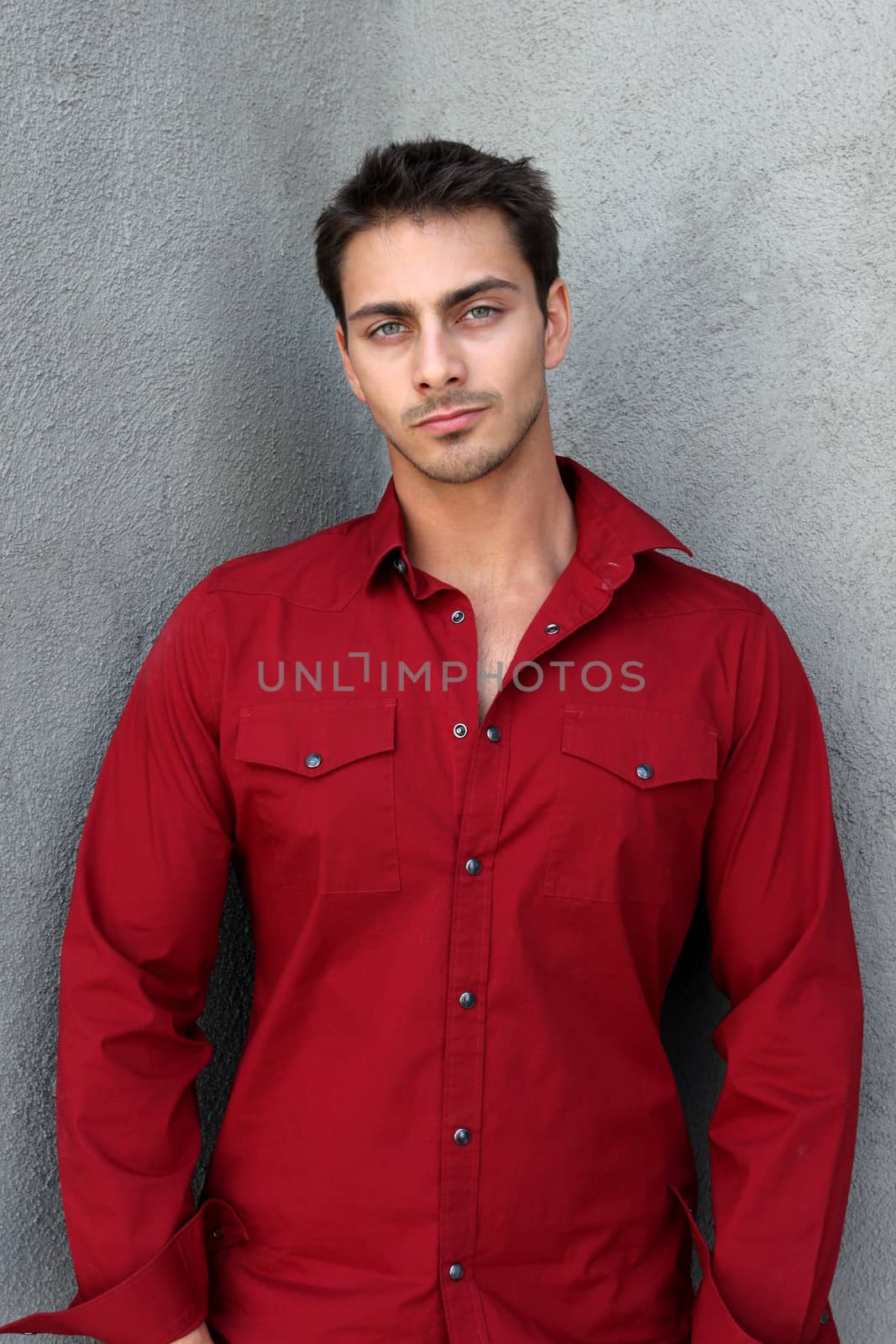 Portrait of a man with red shirt in fornt gray wall.