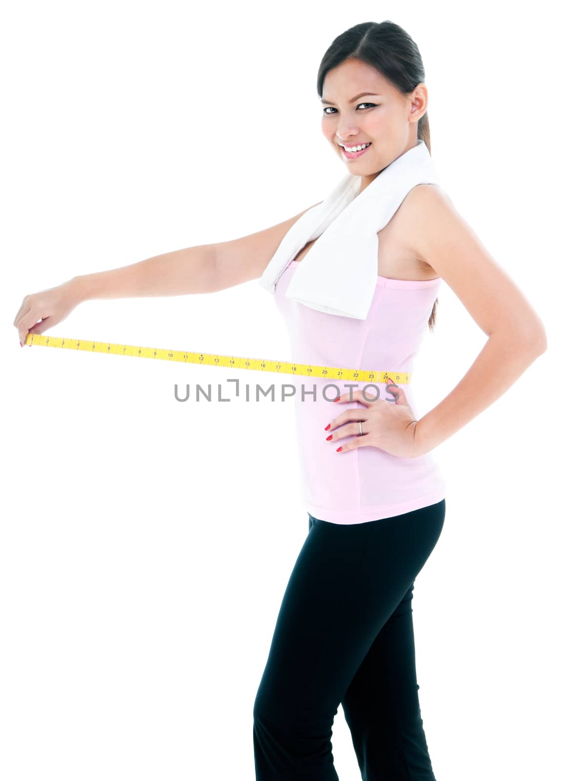 Portrait of a young fitness woman measuring her waist over white background