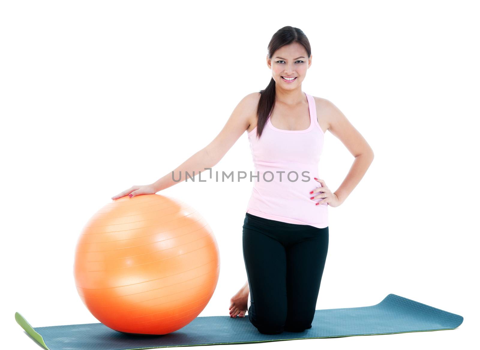 Portrait of an attractive fitness woman kneeling with balance ball.
