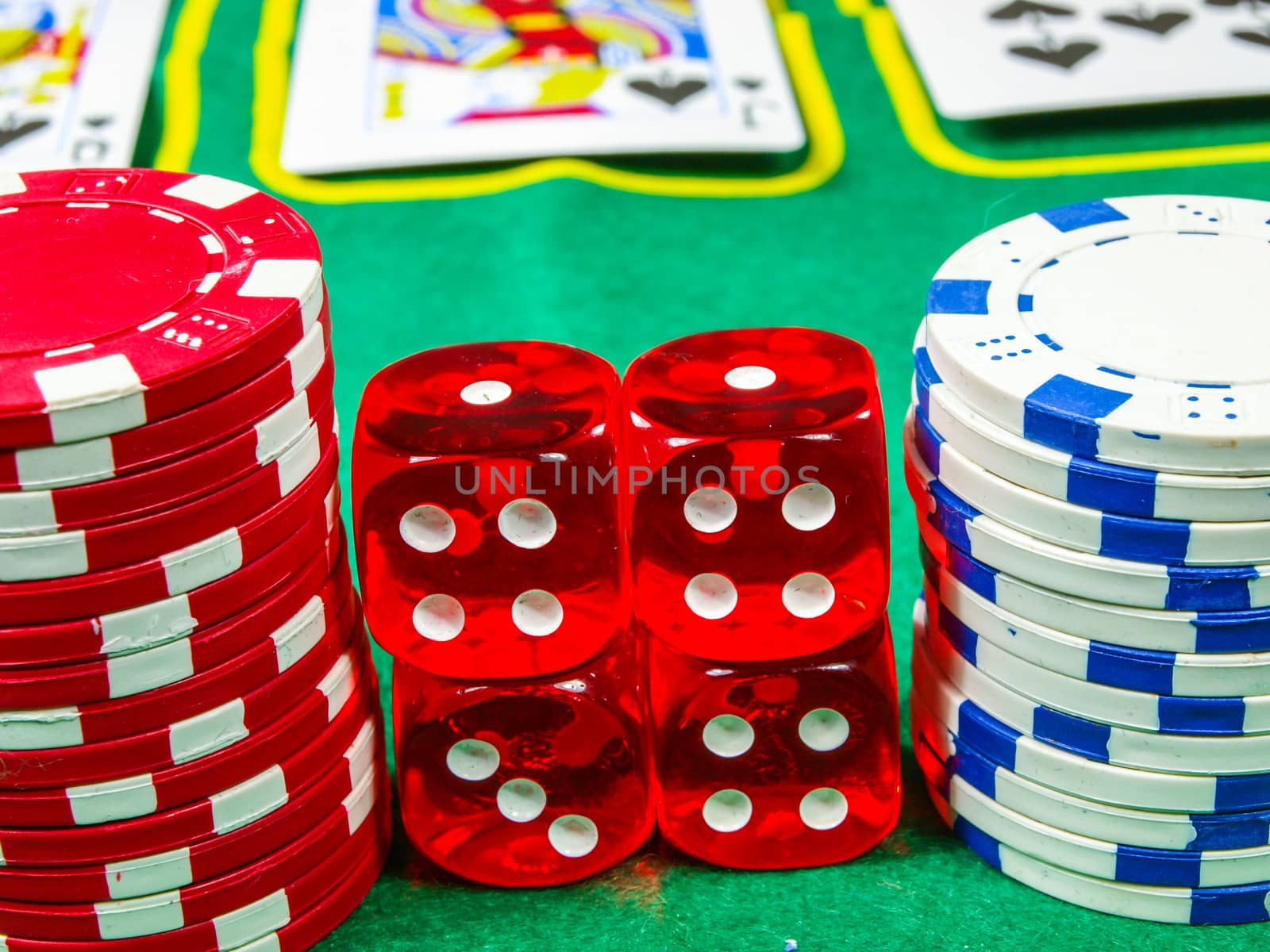 Gambling chips over green table cover with set of cards in the background
