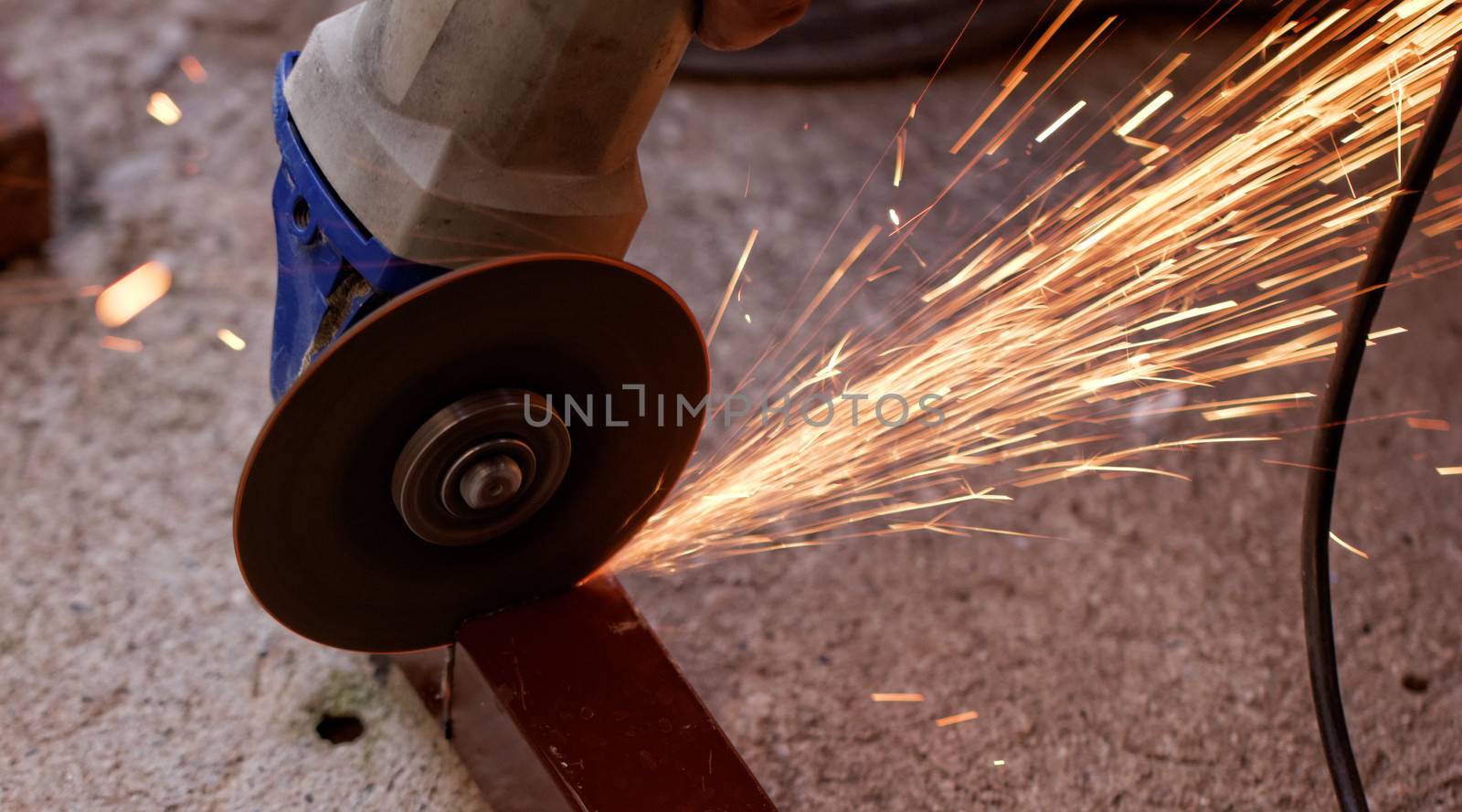 Metal sawing with hand grinder. Sparks while grinding iron.