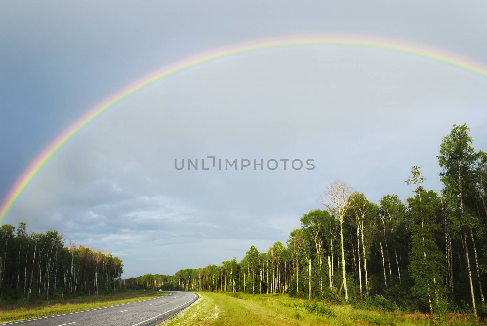 Rainbow after rain over highway in the summer