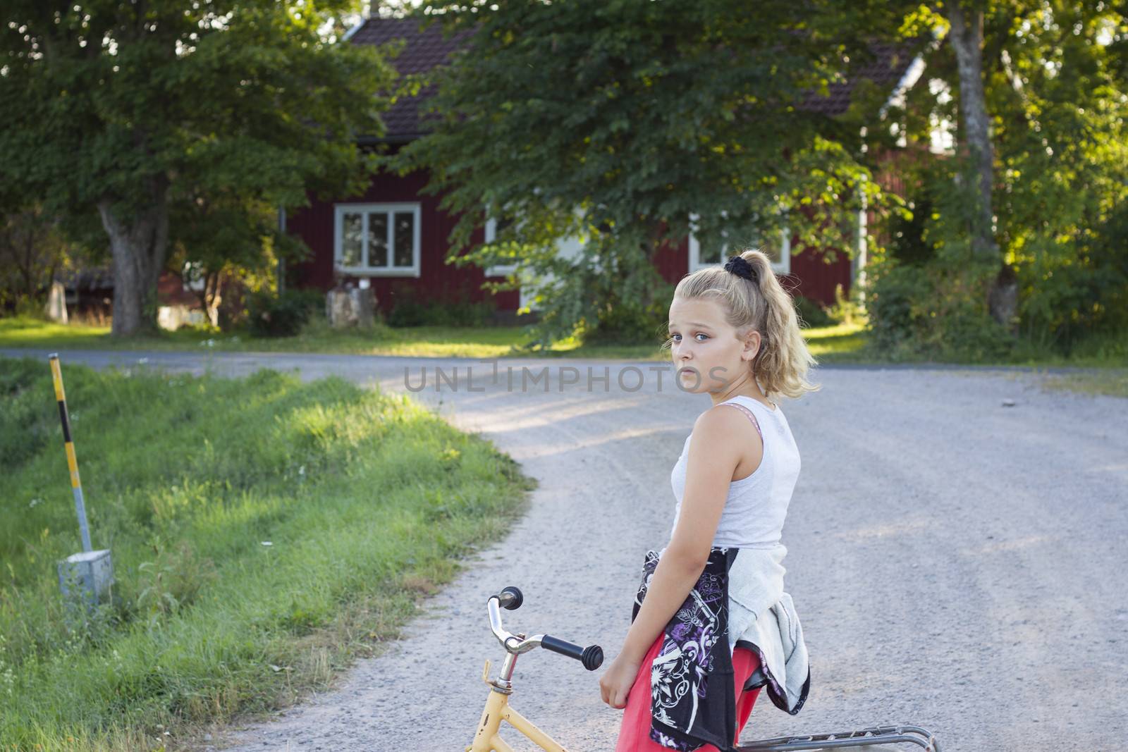 An alone girl looking upset on a bicycle in a rural area in Sweden