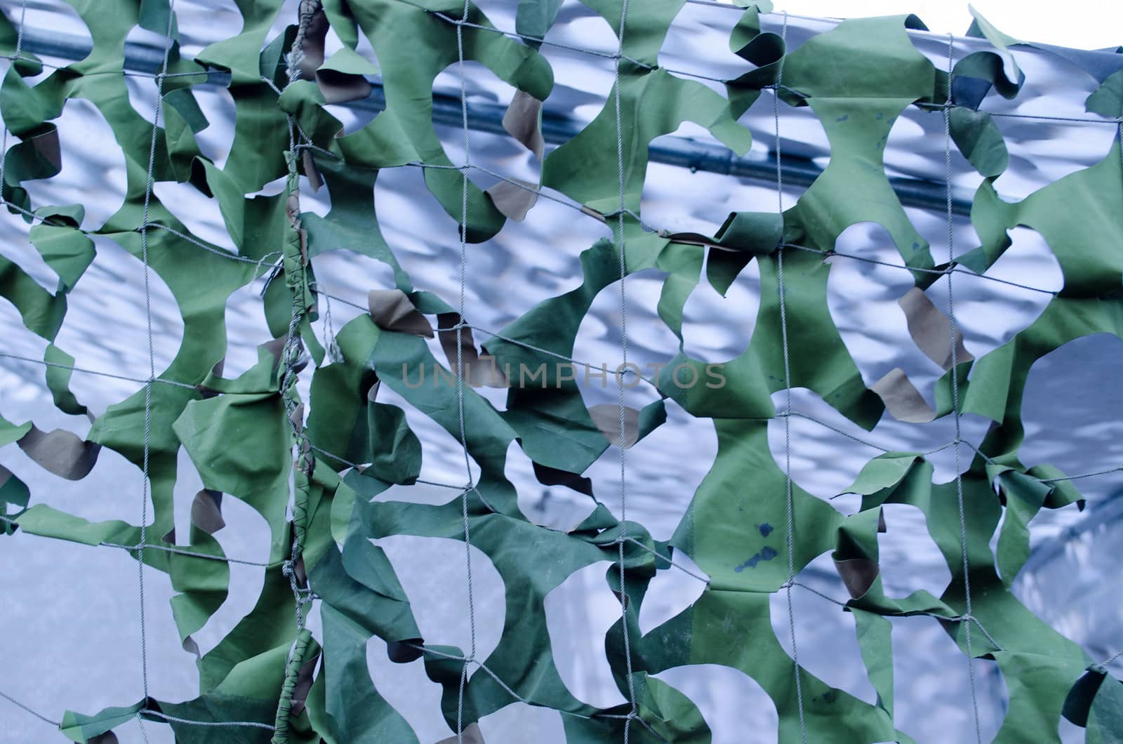 background of camouflage mask colors army tent fabric with holes closeup.