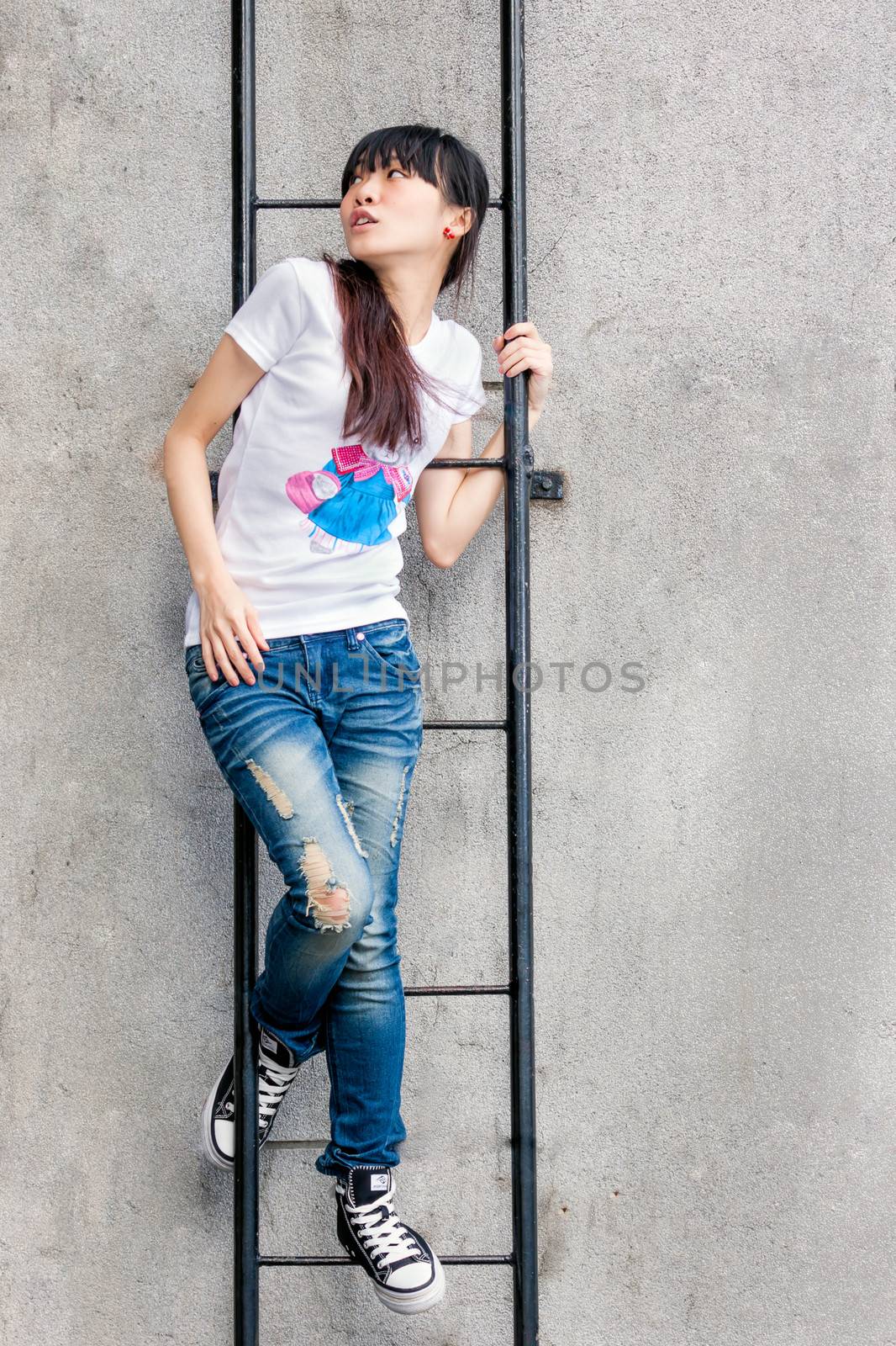 Asian girl on a ladder by limestone wall