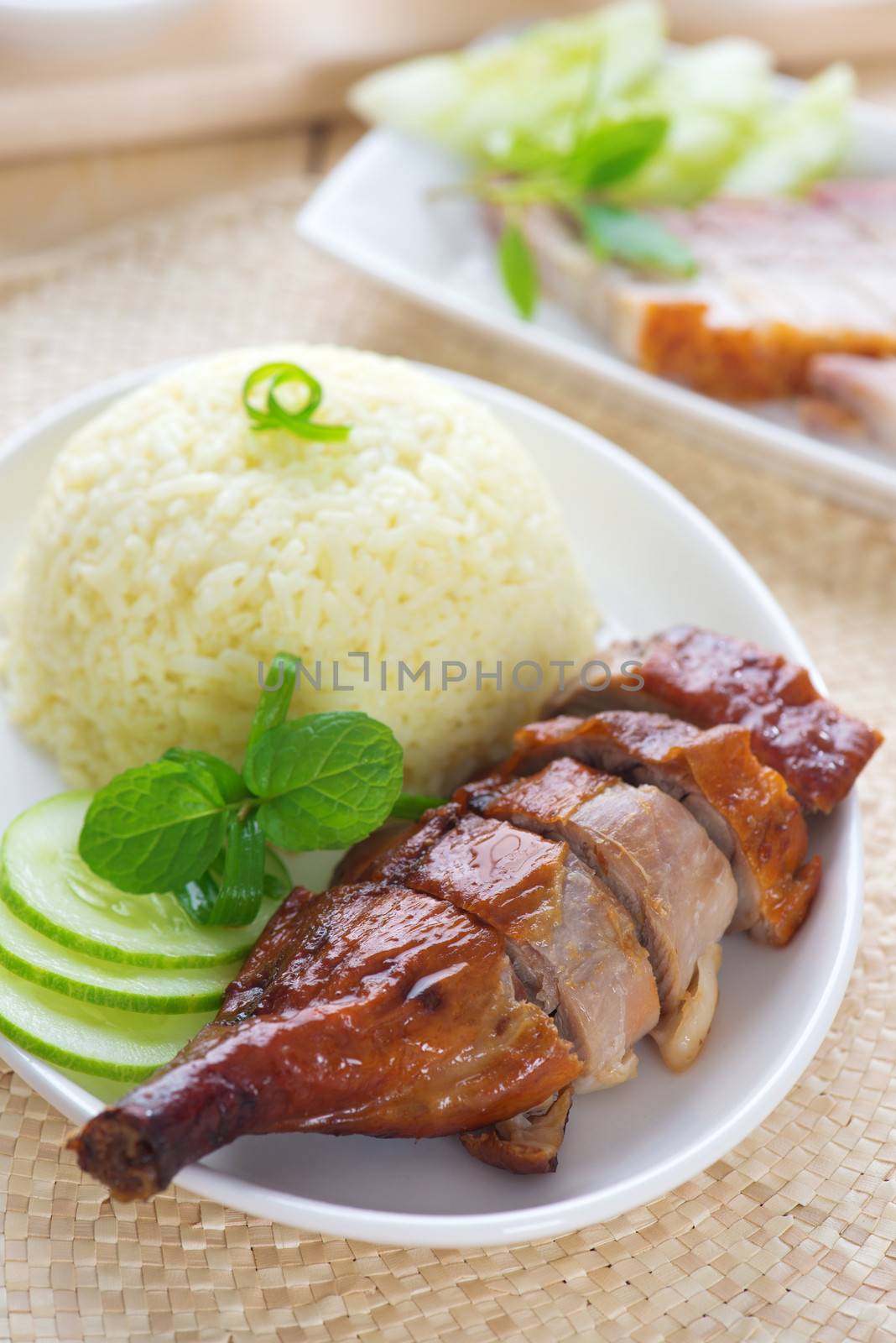 Roasted duck and roasted pork crispy siu yuk, Chinese style, served with steamed rice on dining table. Singapore cuisine.
