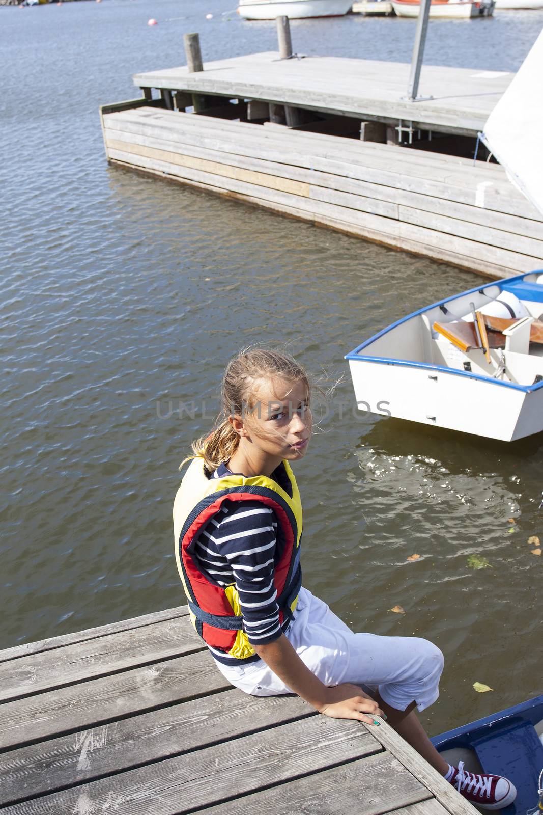 A gril sitting on a yetti with her optimist sailing boat