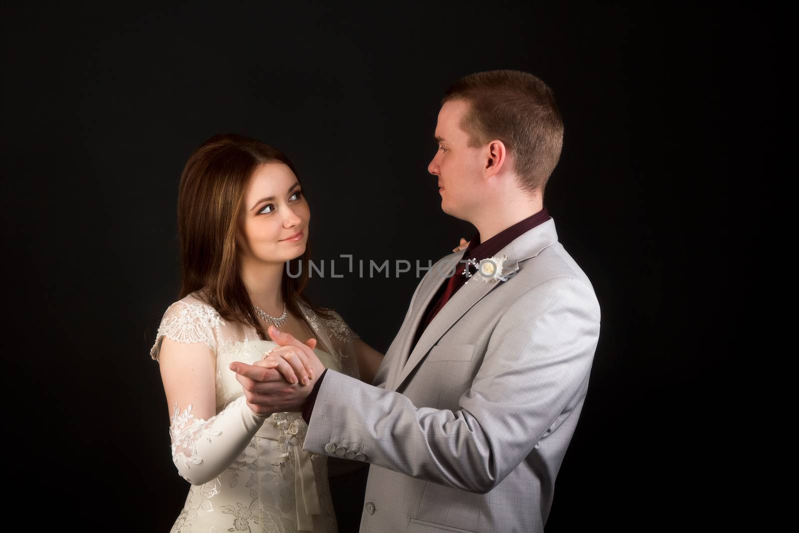 Happy newlyweds dancing on a black background