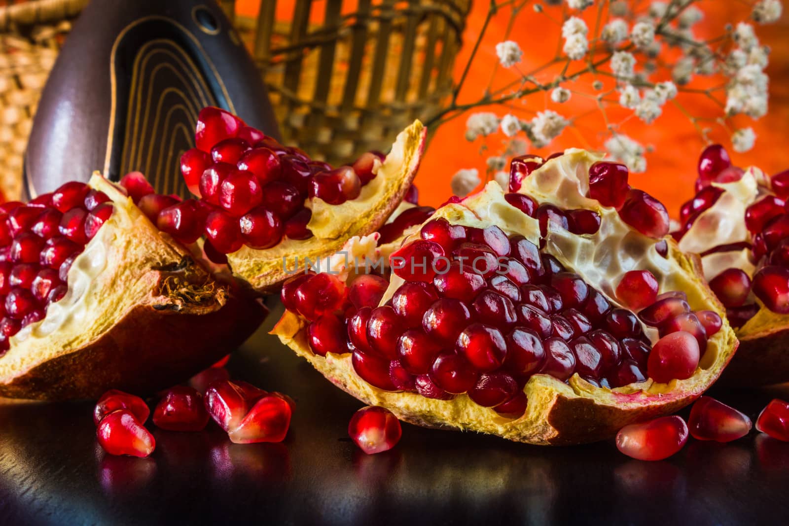 Ripe juicy fruit of the broken pomegranate on a colored background