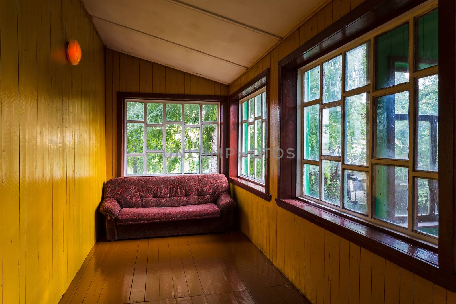 Empty spacious veranda with windows and a sofa in a village house