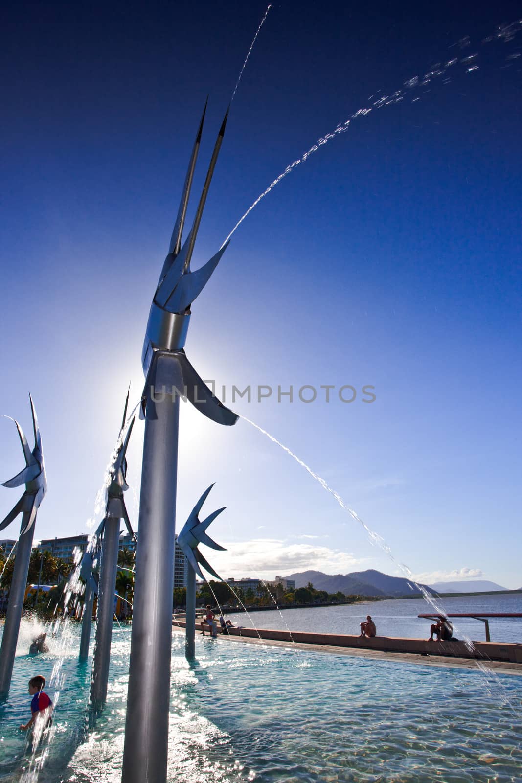 Esplanade Fish Sculptures and fountains in Cairns, Australia with people enjoying the summer sun playing in the water