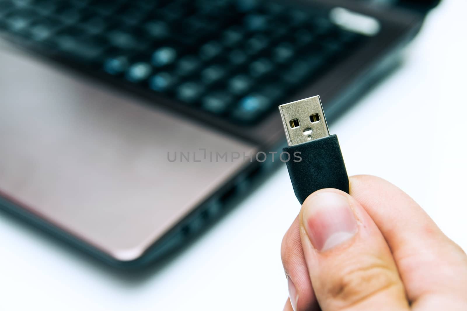 Man holding USB plug. Laptop in background by simpson33
