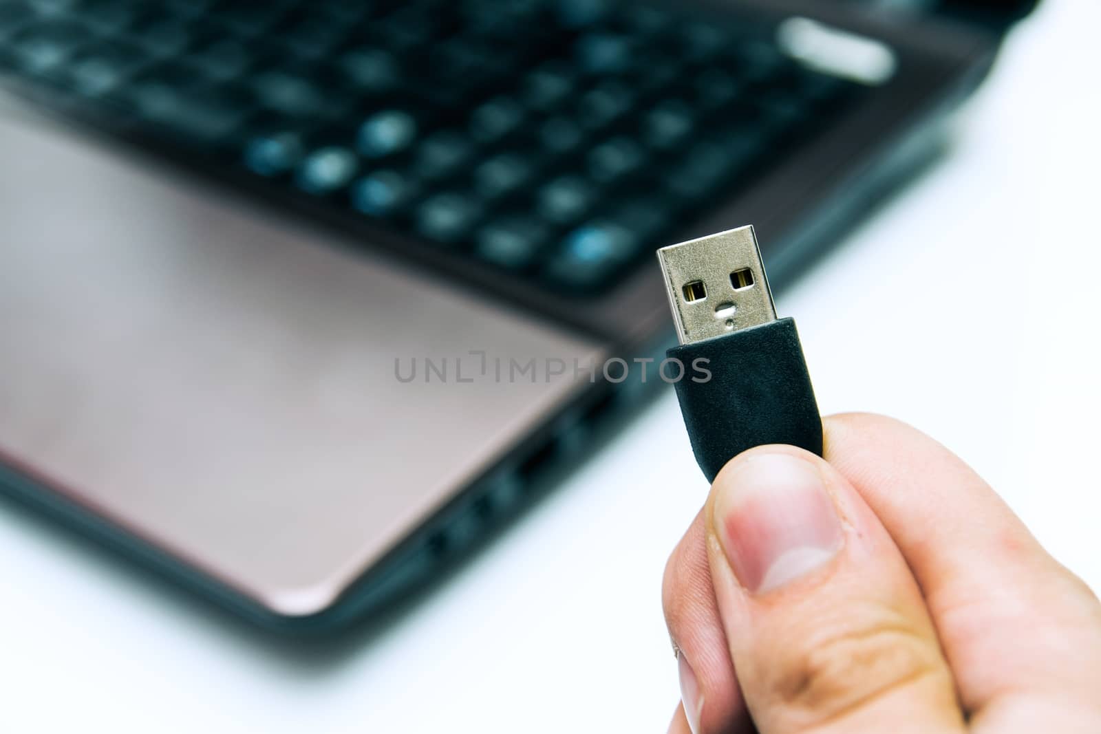 Man holding USB plug. Laptop in background