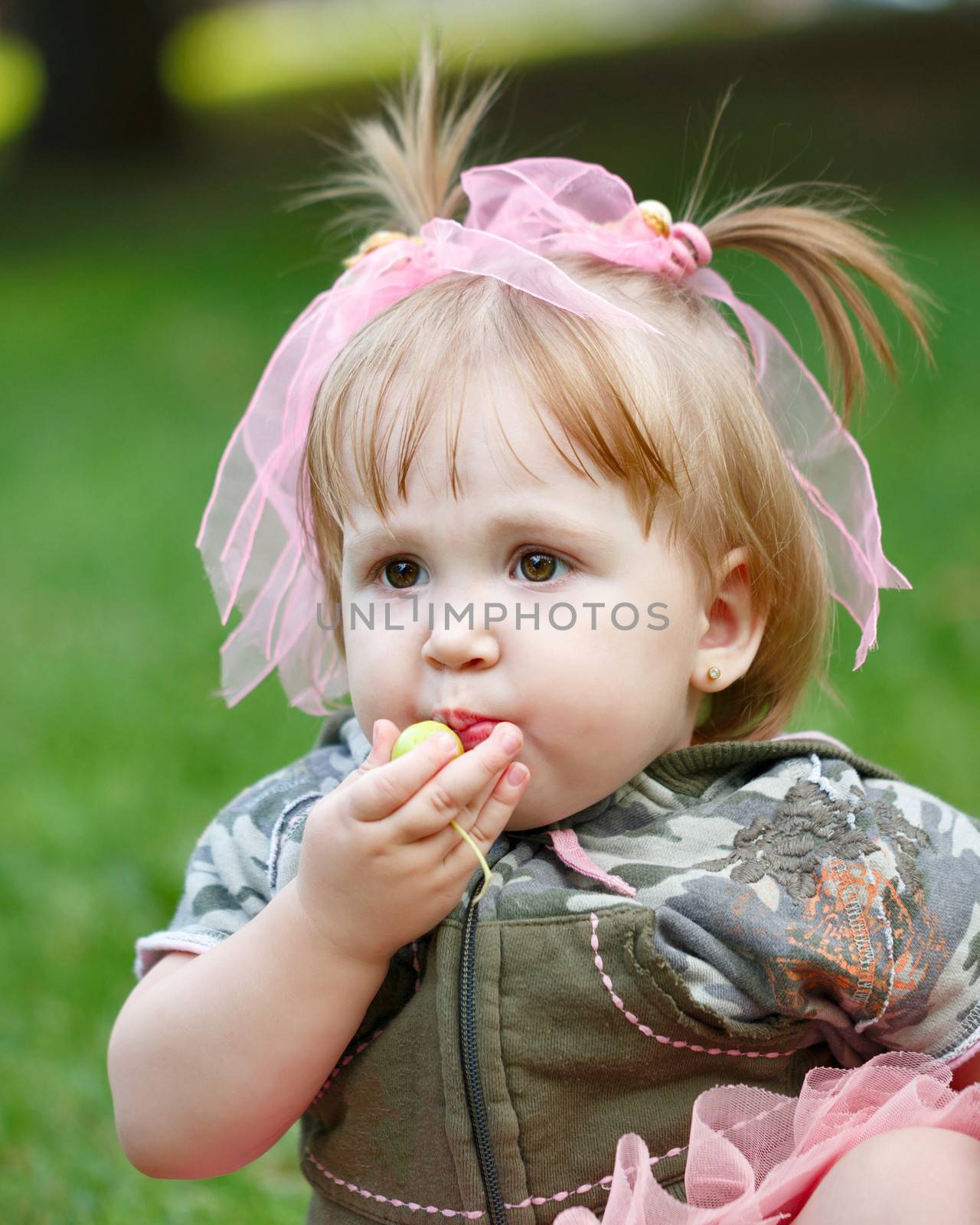 Little blond girl in a blue skirt eating an apple