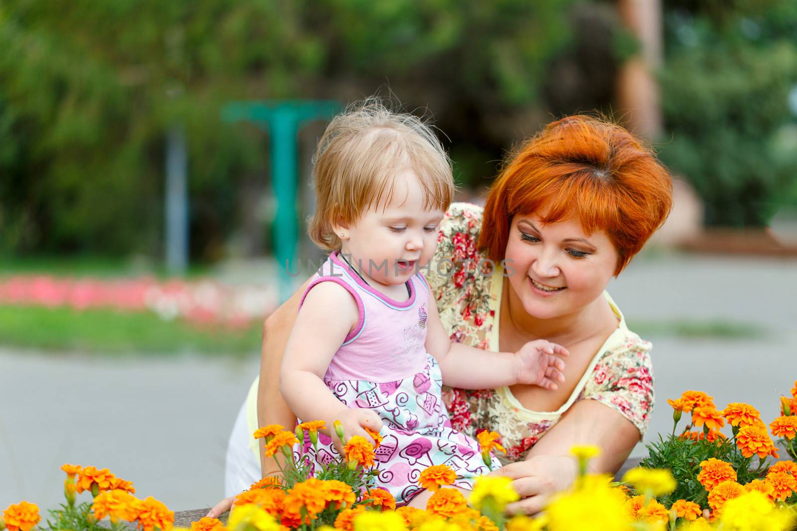 Family, mother hugging her daughter in the park near a flower bed