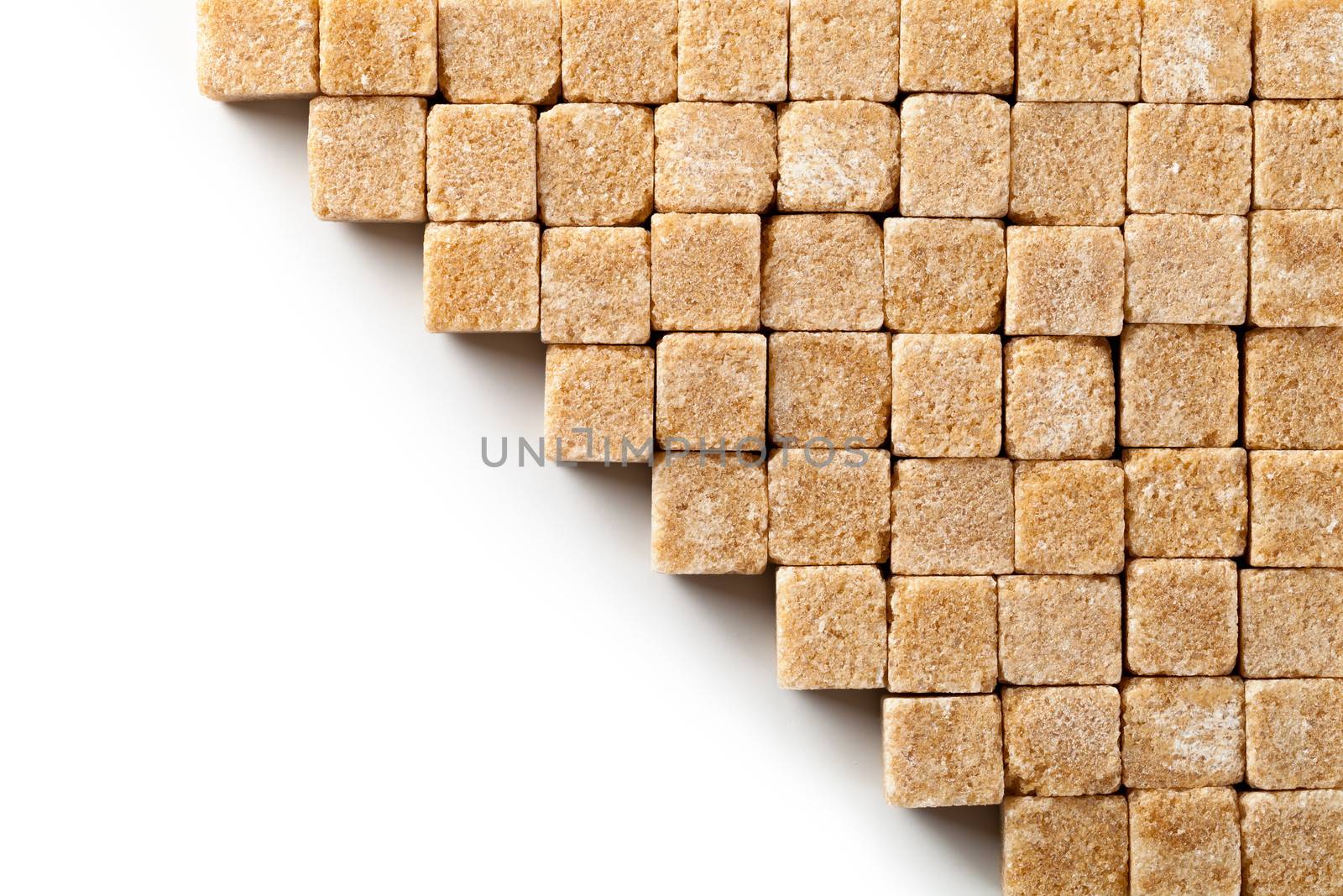 Brown sugar cubes on white background. Copy space. Top view