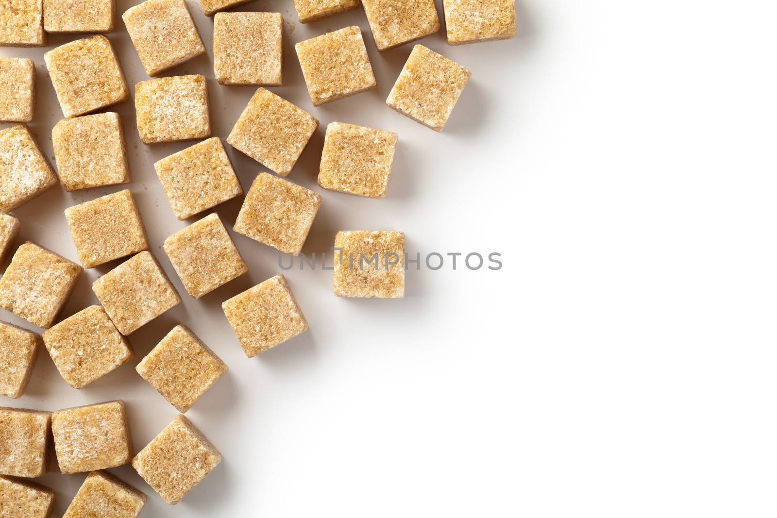 Brown cane sugar cubes on white background. Copy space. Top view