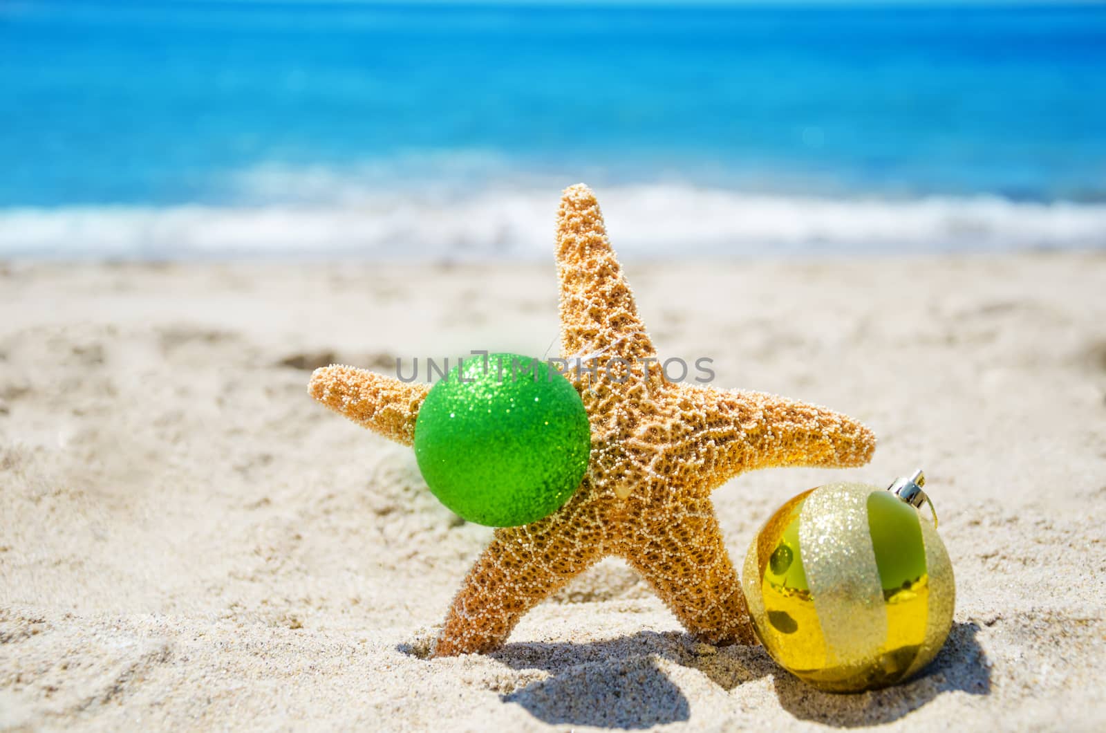 Starfish with Christmas ball on sandy tropical beach in sunny day- holiday concept