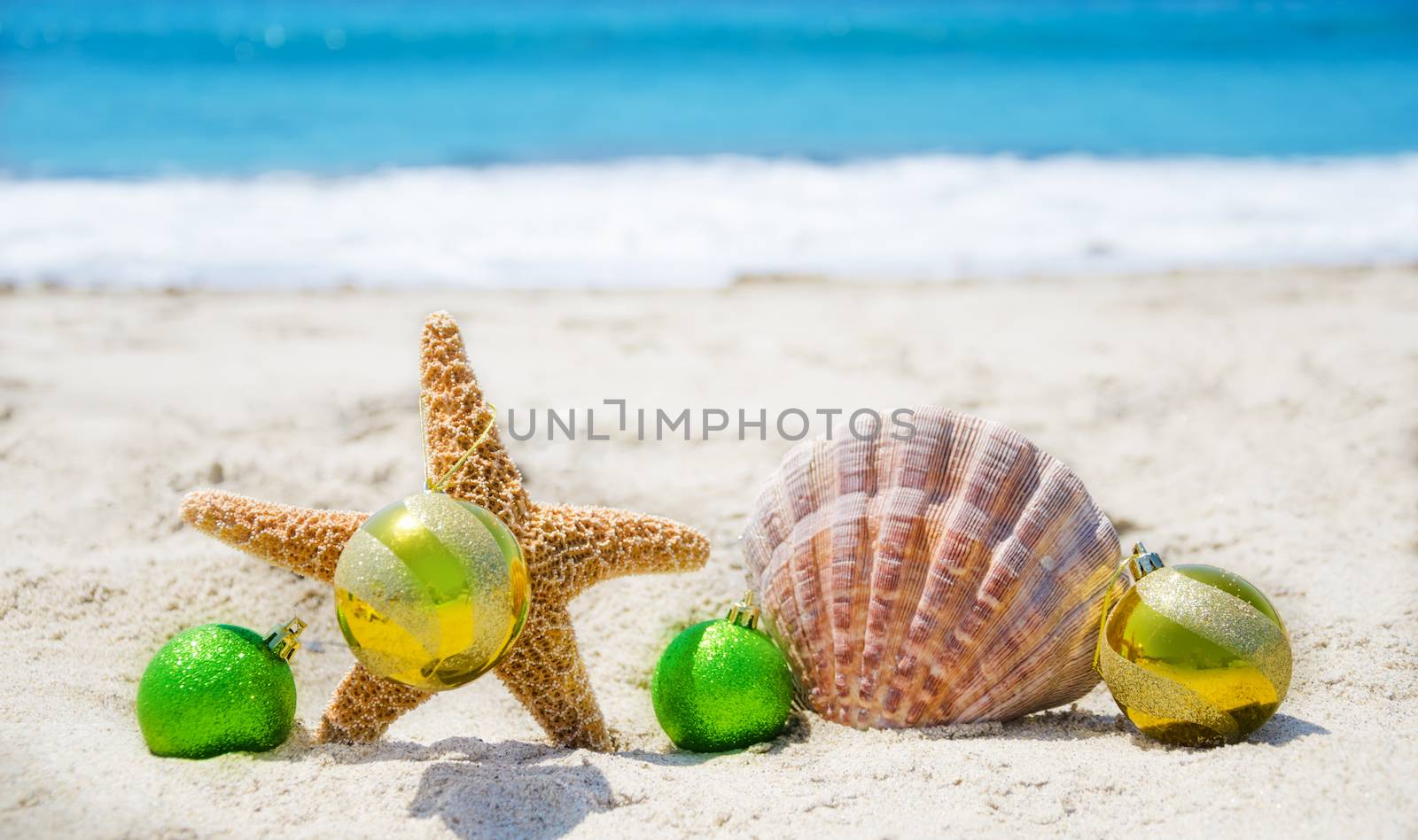 Starfish and seashell with Christmas balls on sandy beach in sunny day- holiday concept
