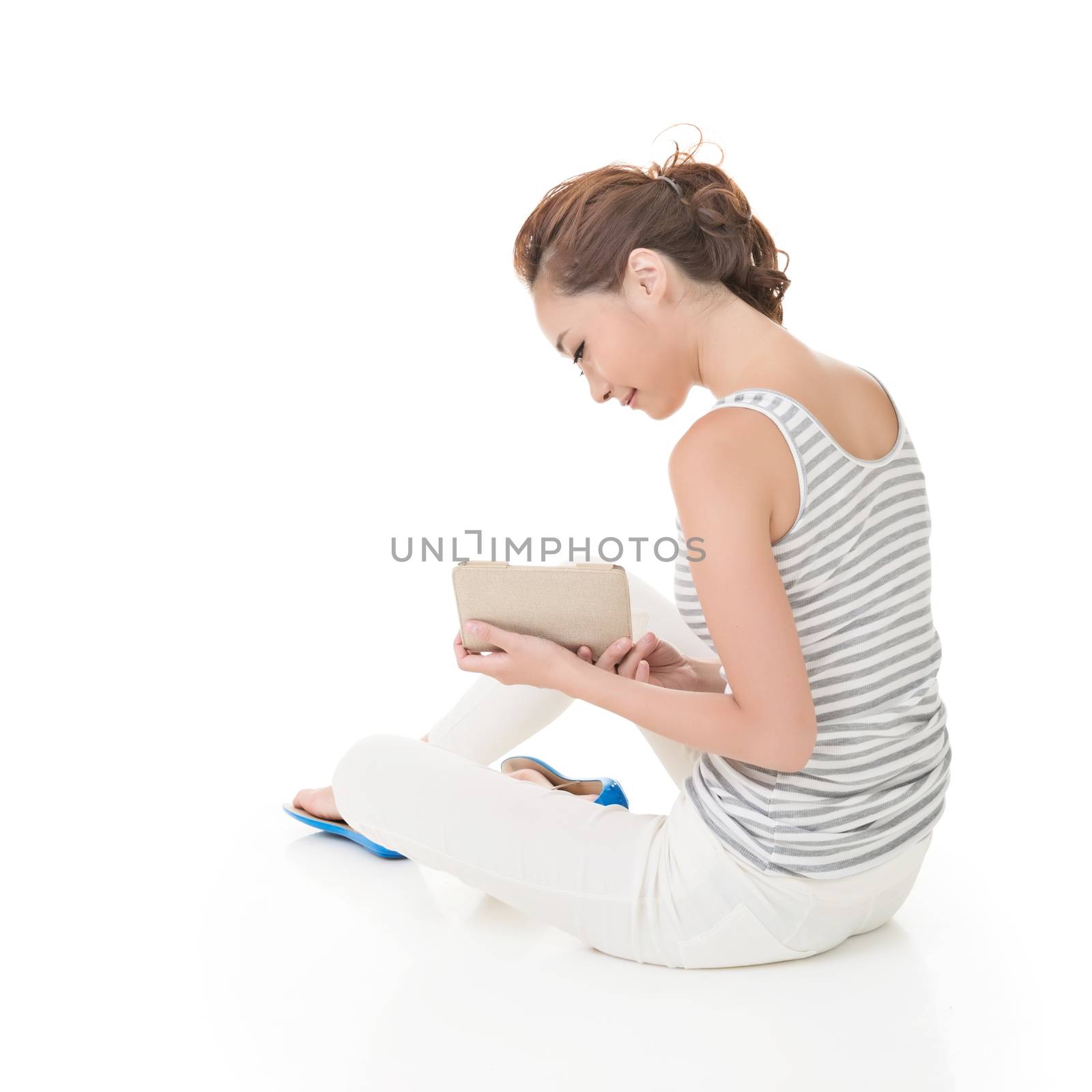 Young woman sit on ground and read a book, full length portrait isolated on white background.