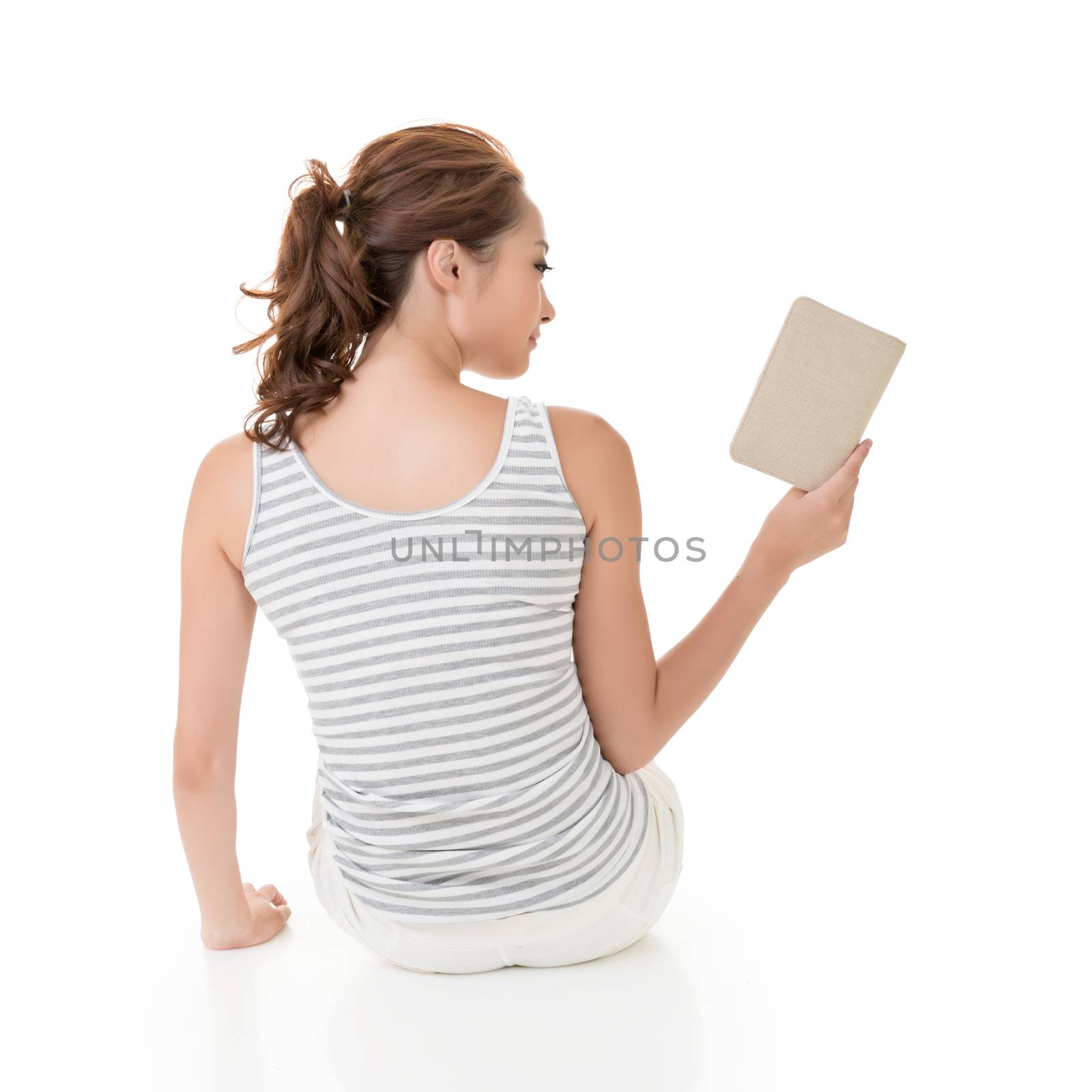 Young woman sit on ground and read a book, full length portrait isolated on white background.