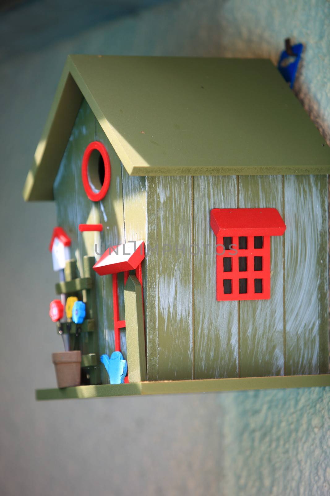 Decorative bird box in the shape of a house hanging on an exterior wall providing a secure place for wild birds to nest and breed