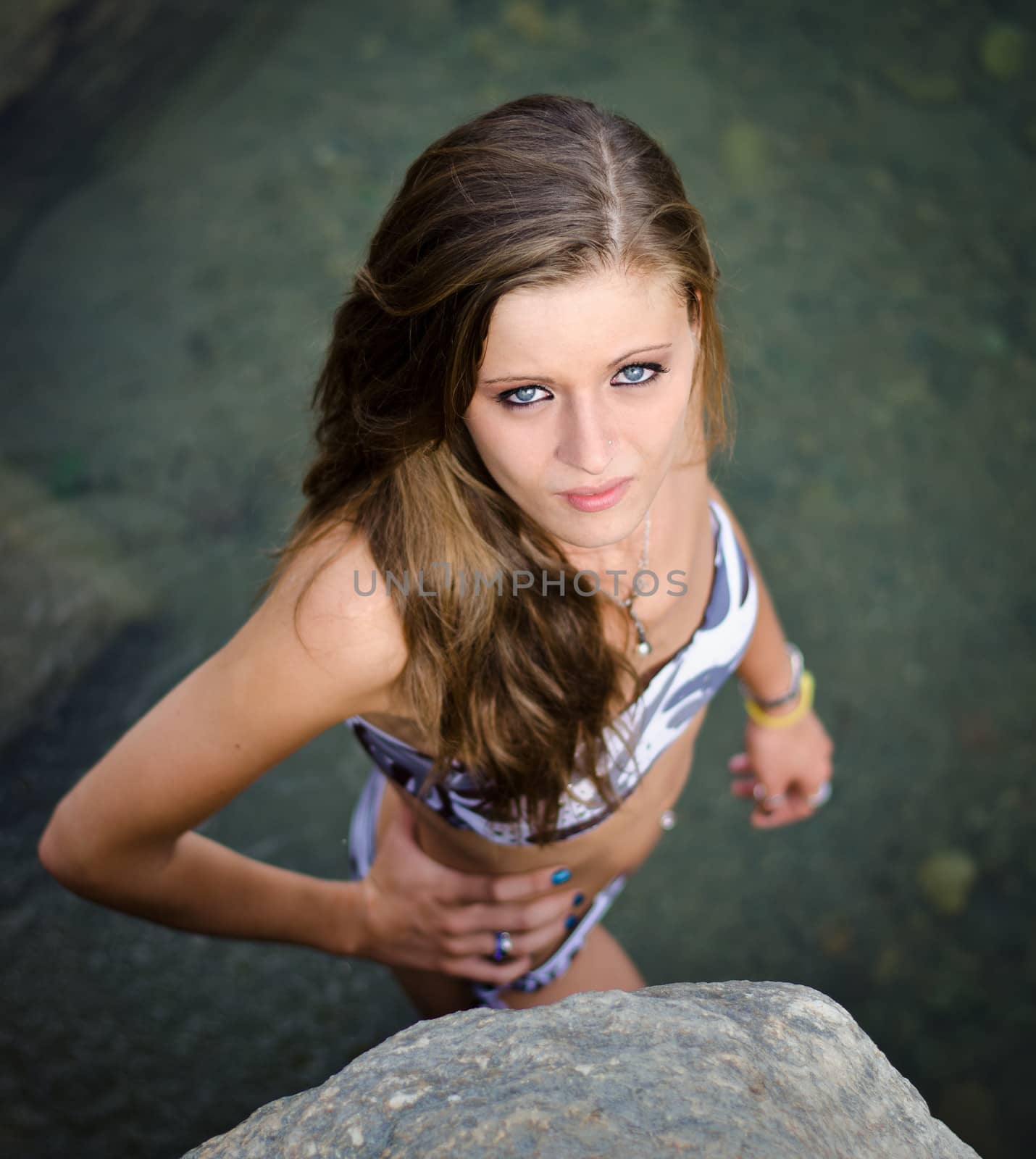 Attractive girl standing in a water pond wearing swimsuit shot from above