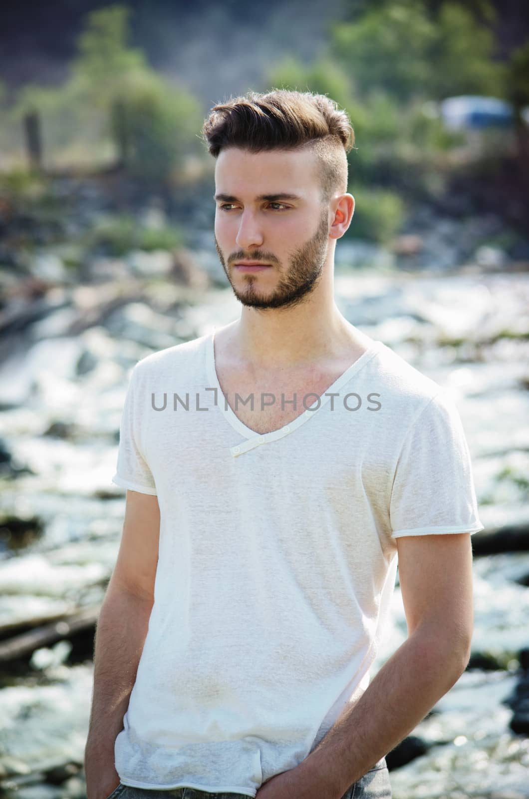 Portrait of handsome young man in white t-shirt outdoors, looking to a side