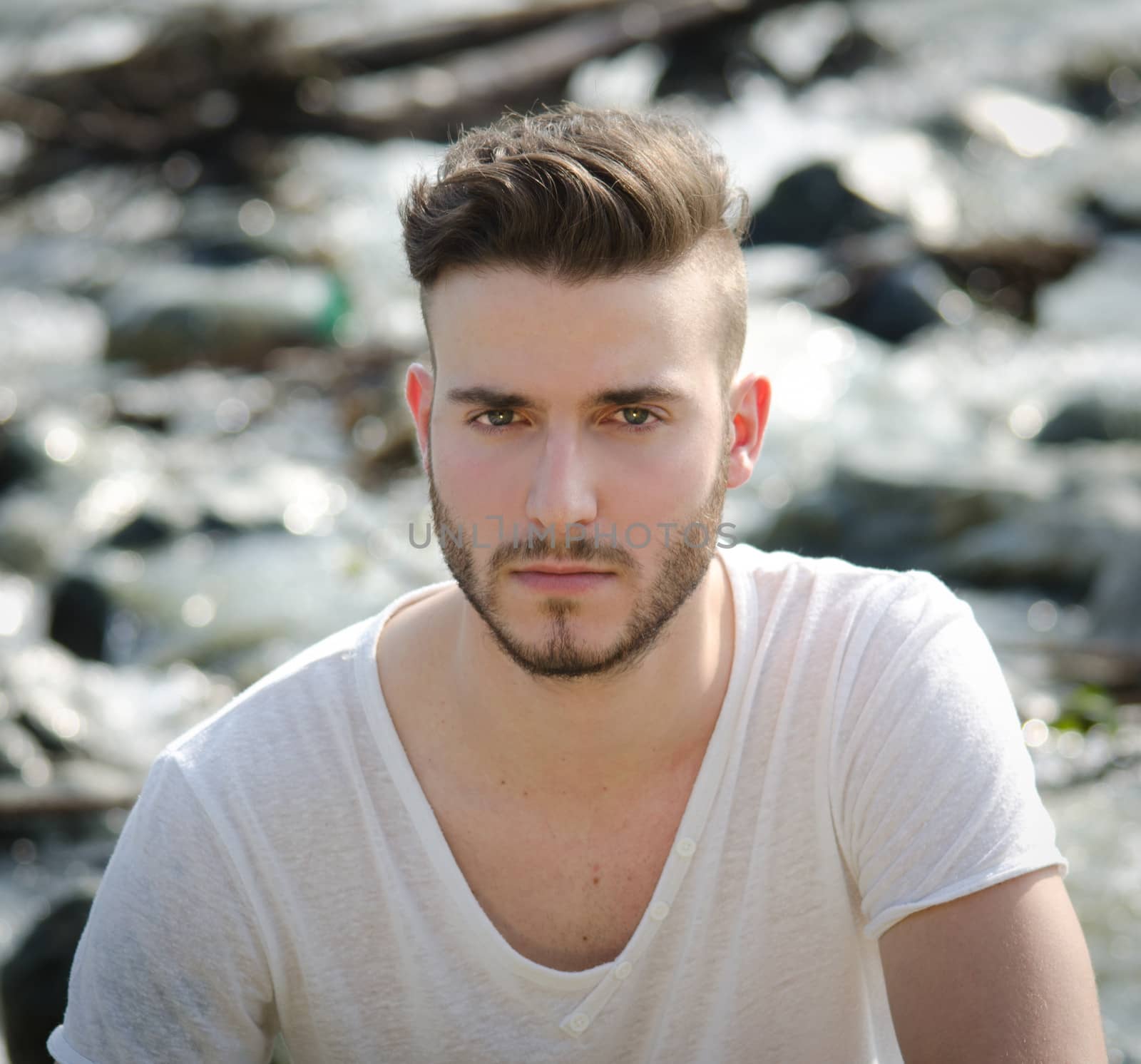 Portrait of handsome young man in white t-shirt outdoors, looking in camera