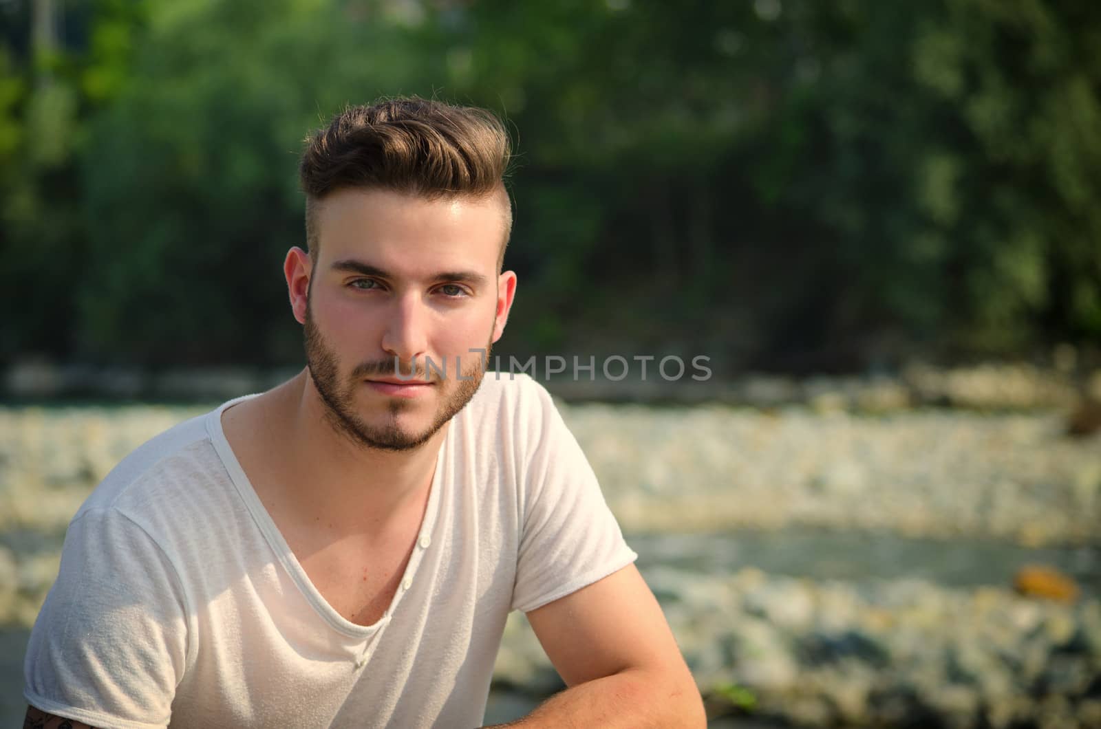 Portrait of handsome young man in white t-shirt outdoors, looking in camera