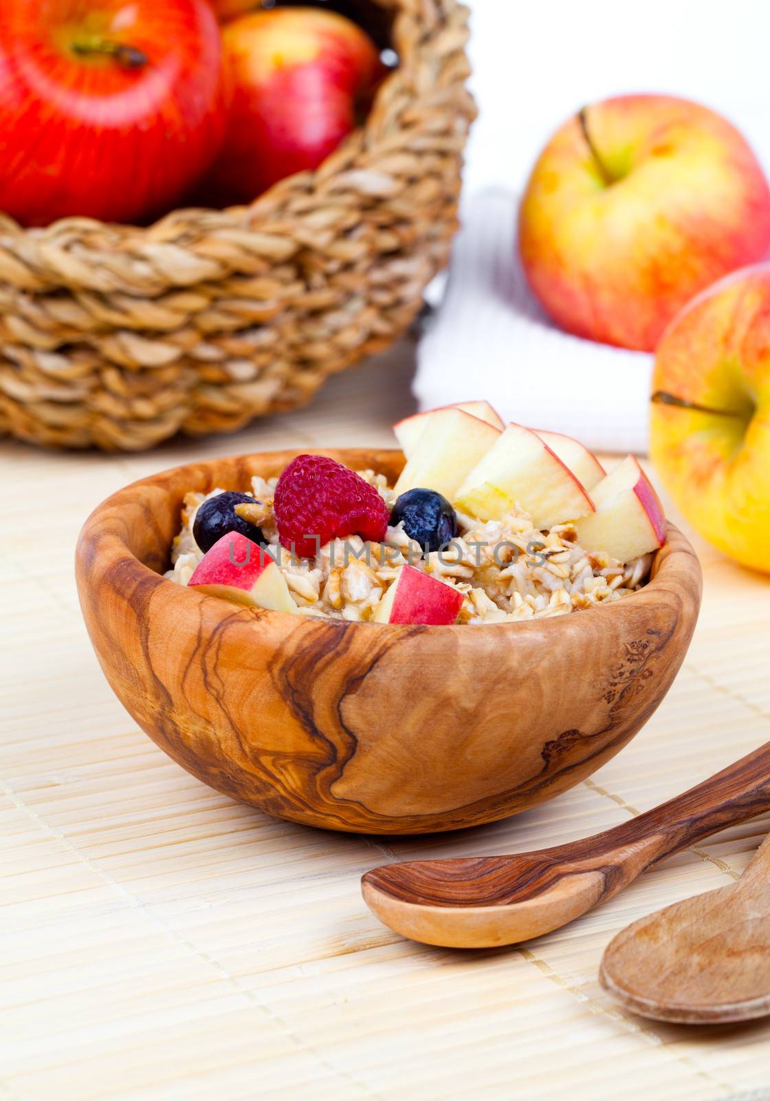 tasty oatmeal with raspberries and apple in the wooden bowl by motorolka