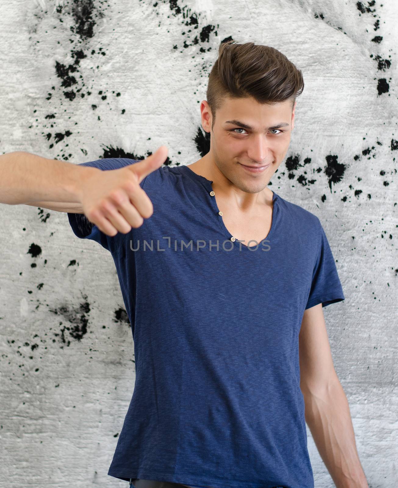 Handsome young man doing thumb up sign by artofphoto