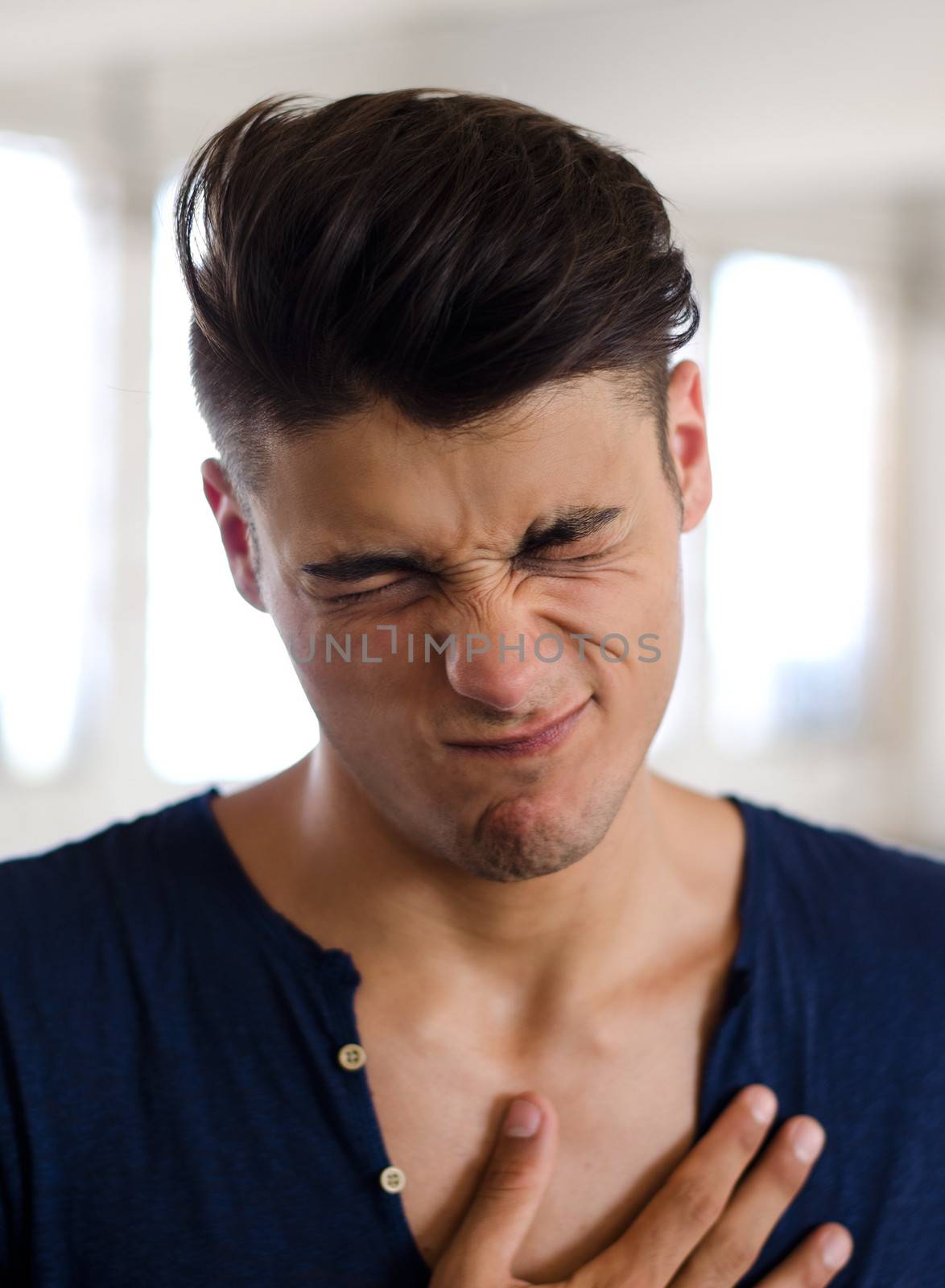 Handsome young man doing funny face, looking disgusted or displeased