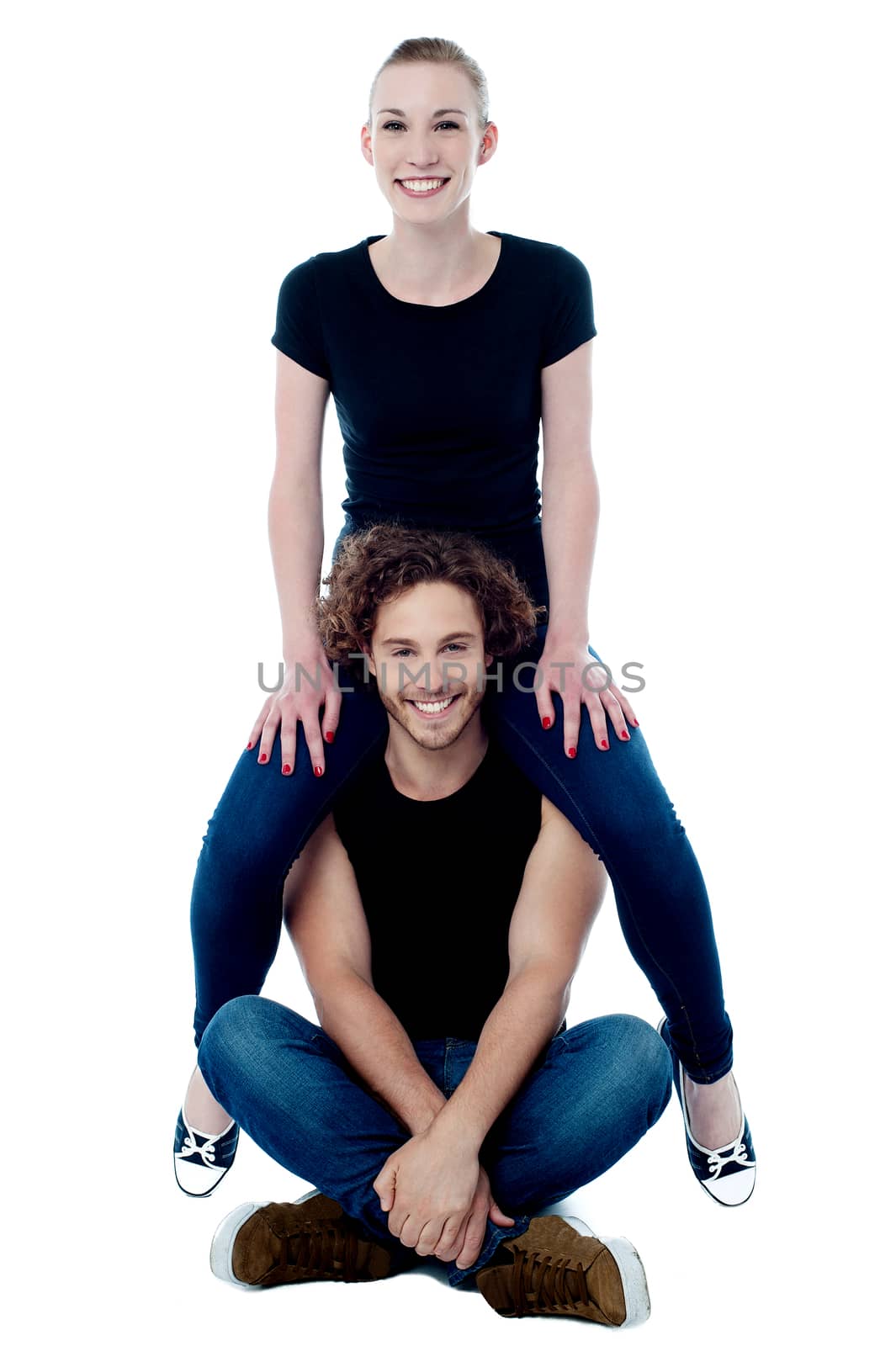 Girl sitting on boyfriend's shoulders by stockyimages