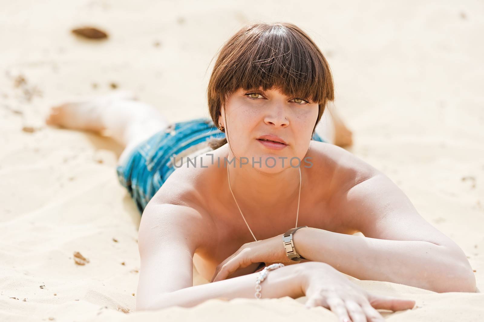 Young slim girl sunbathing on the sand