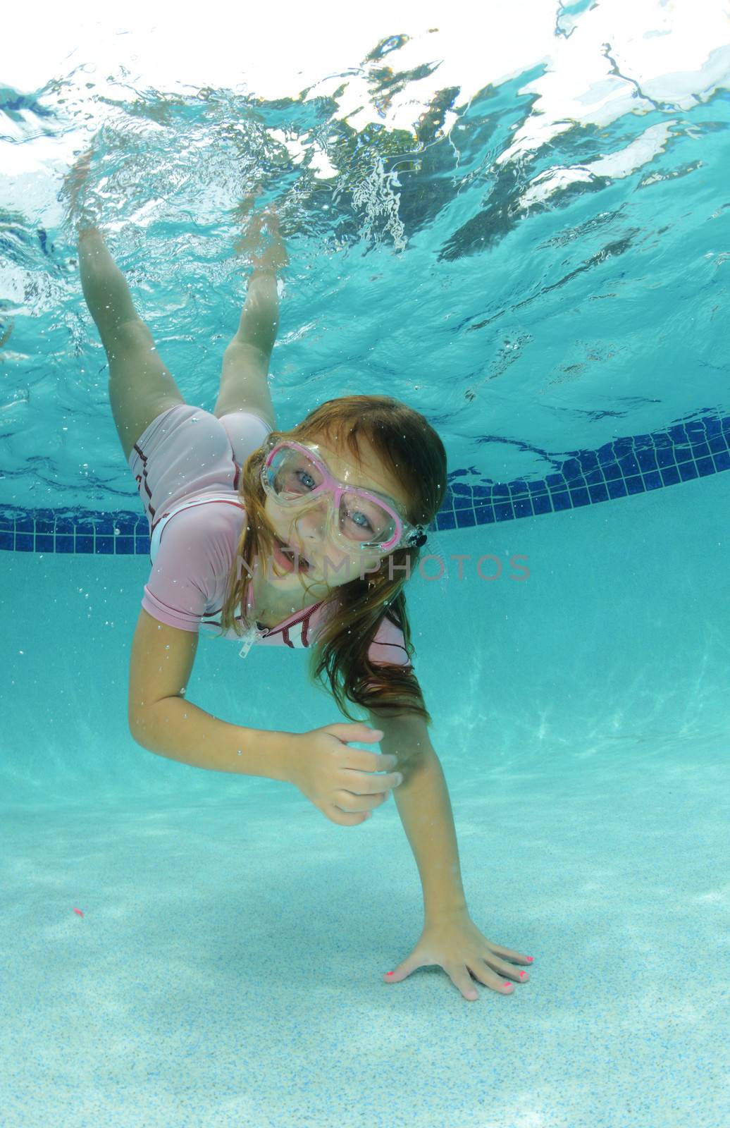 pretty young girl swimming to bottom of pool