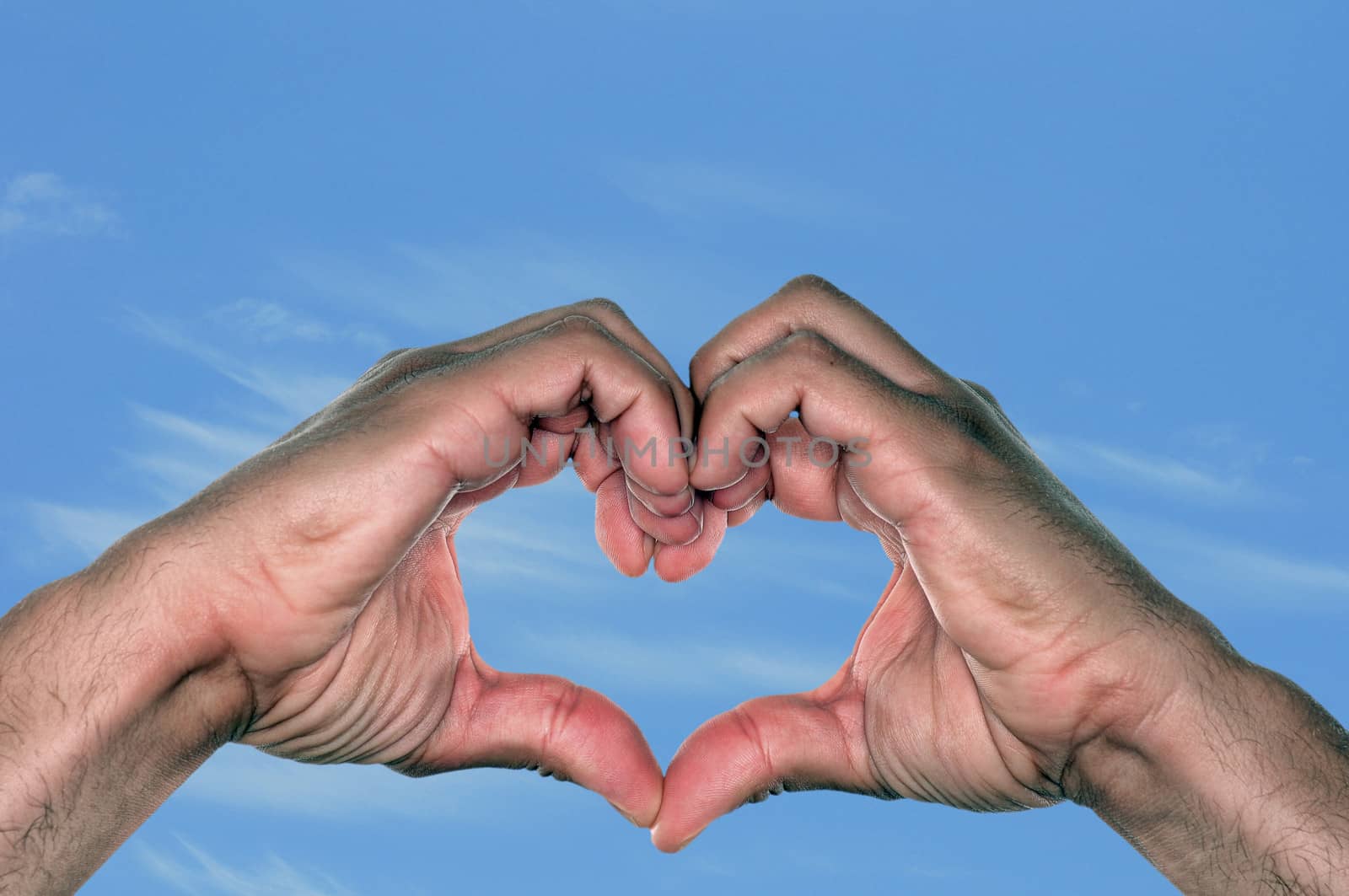 Love and hands in the shape of a heart against a blue sky on a warm day
