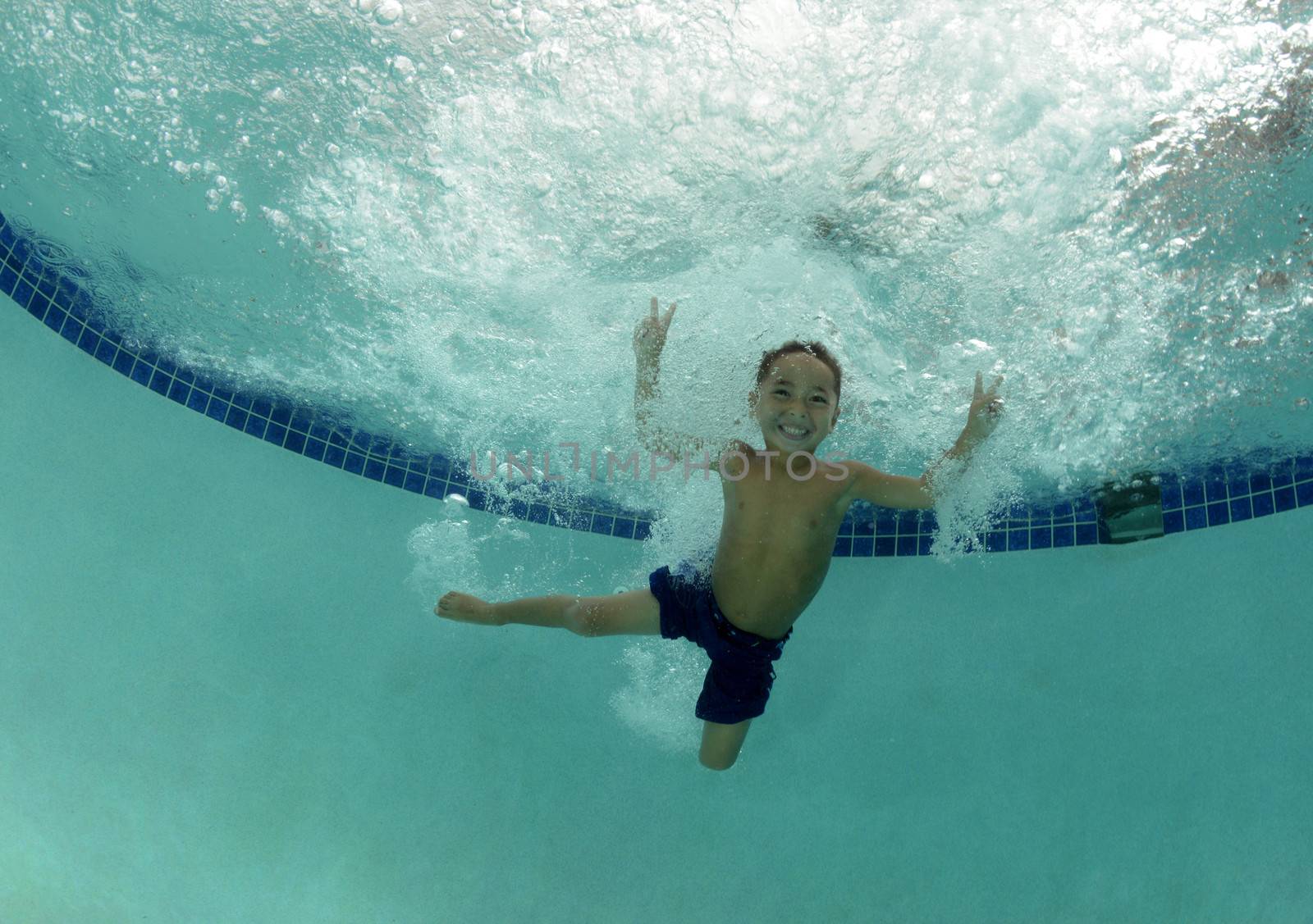 child smiling underwater in swimming pool