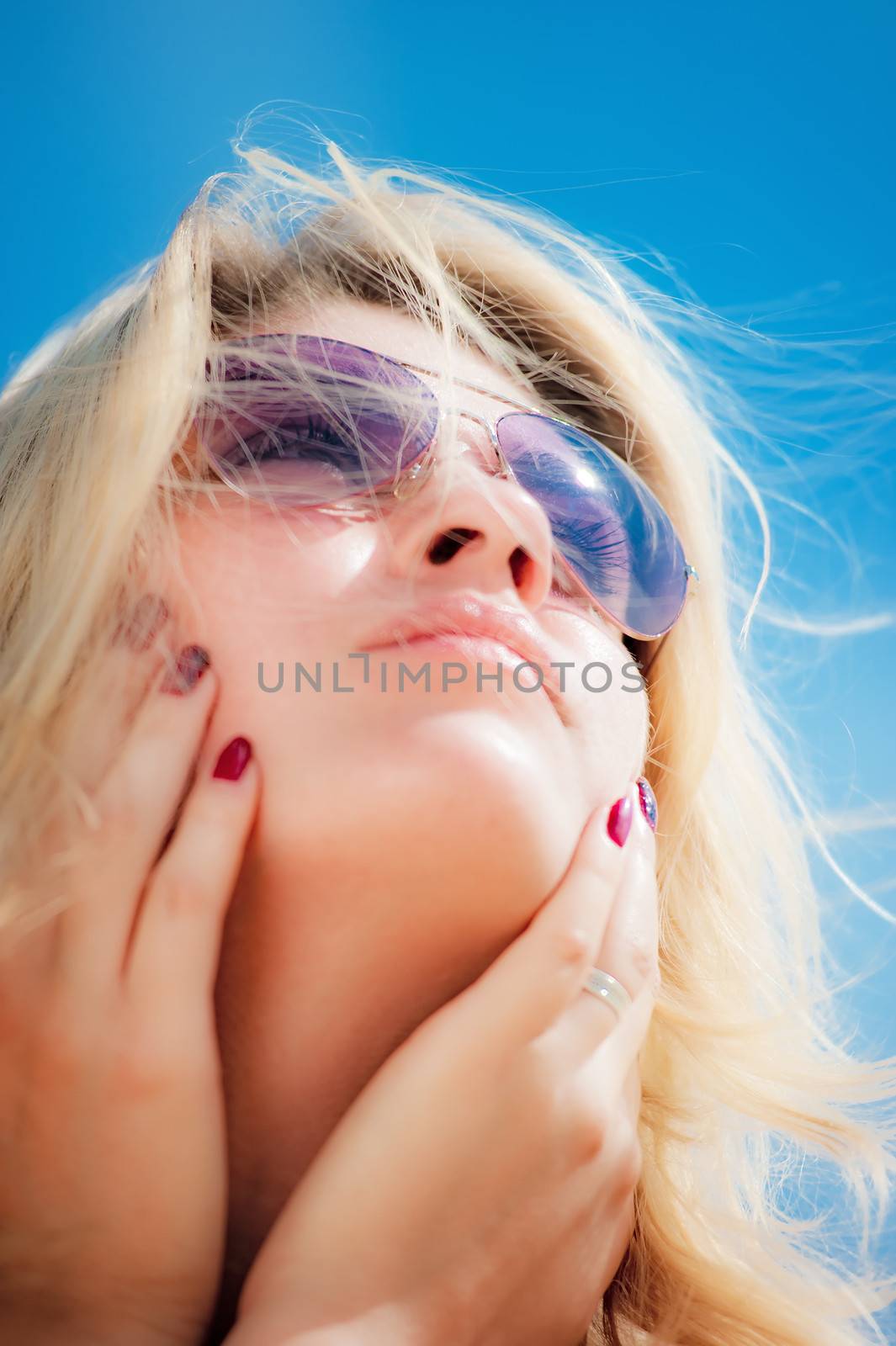 Portrait of a young woman wearing sunglasses, looking to the sky.
