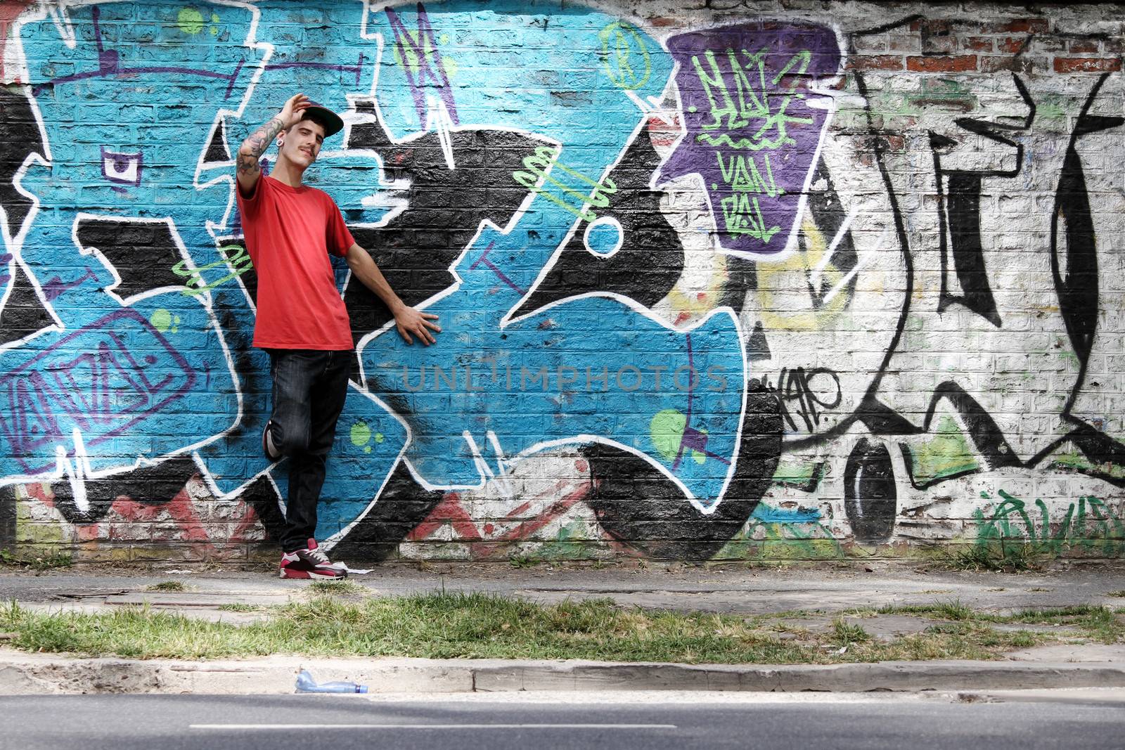 A greeting young Rapper greeting in front of a Graffiti wall.