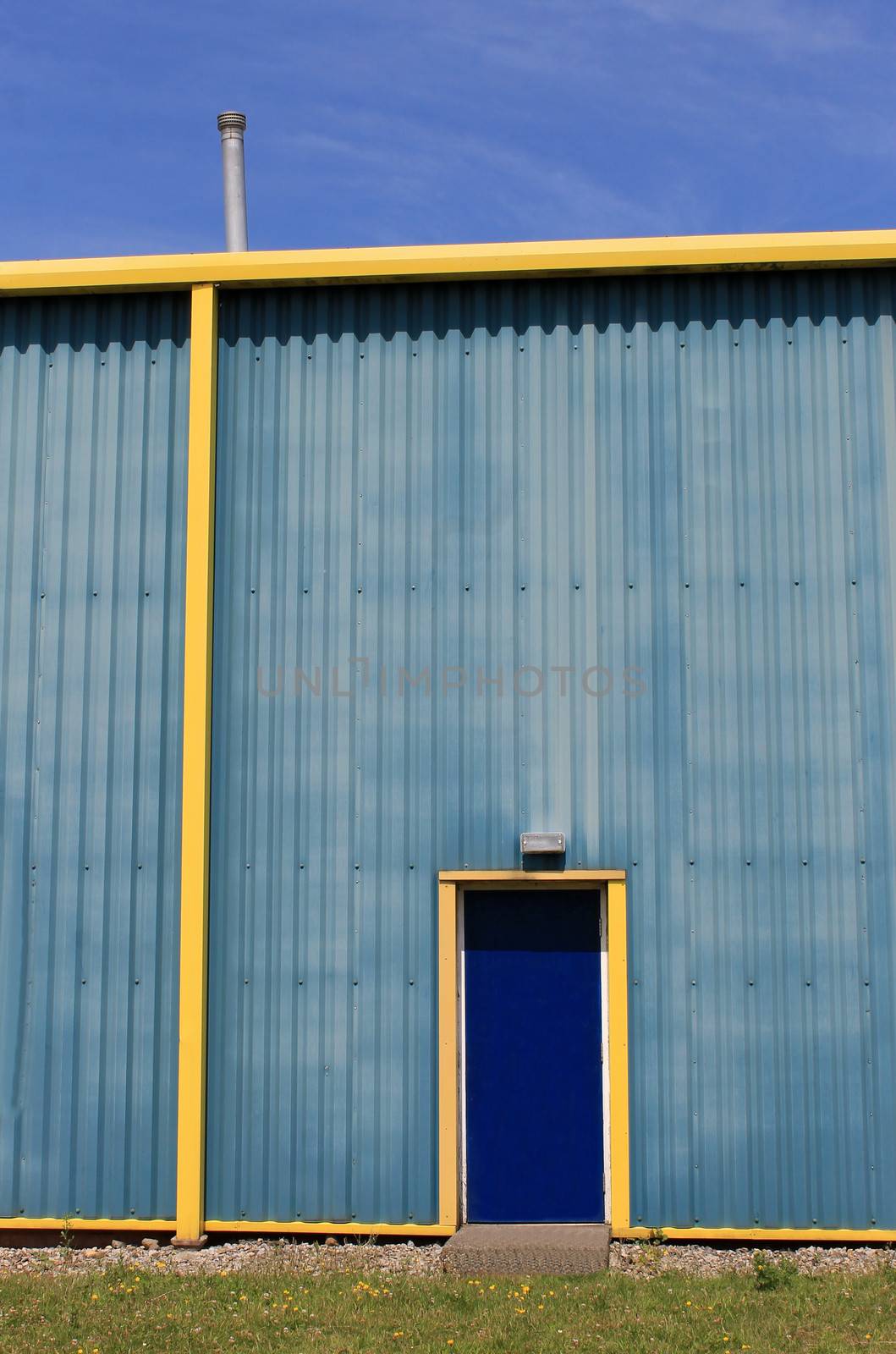 Exterior of blue and yellow modern warehouse building, sky background.