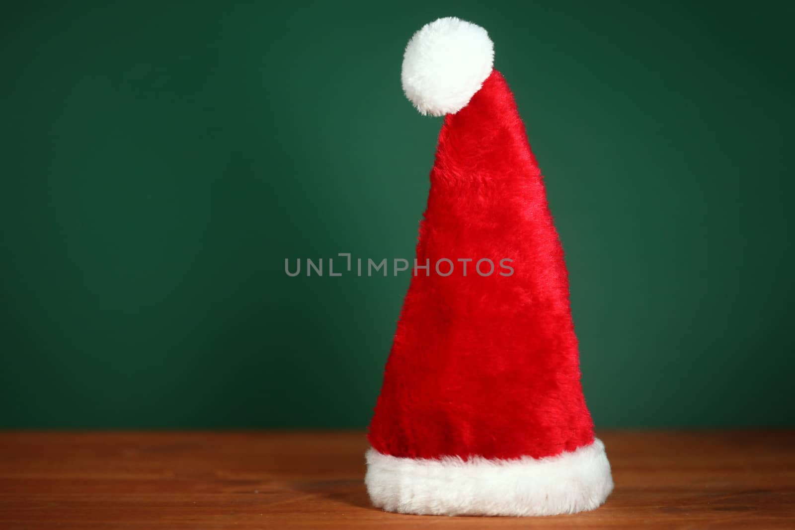 Santa Clause Red Hat With Copy Space on Green and Wood Background