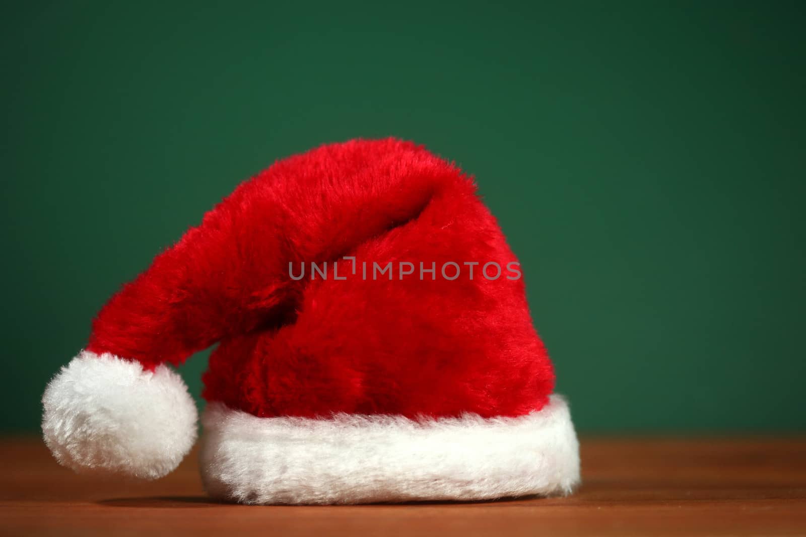 Santa Clause Red Hat With Copy Space on Green and Wood Background